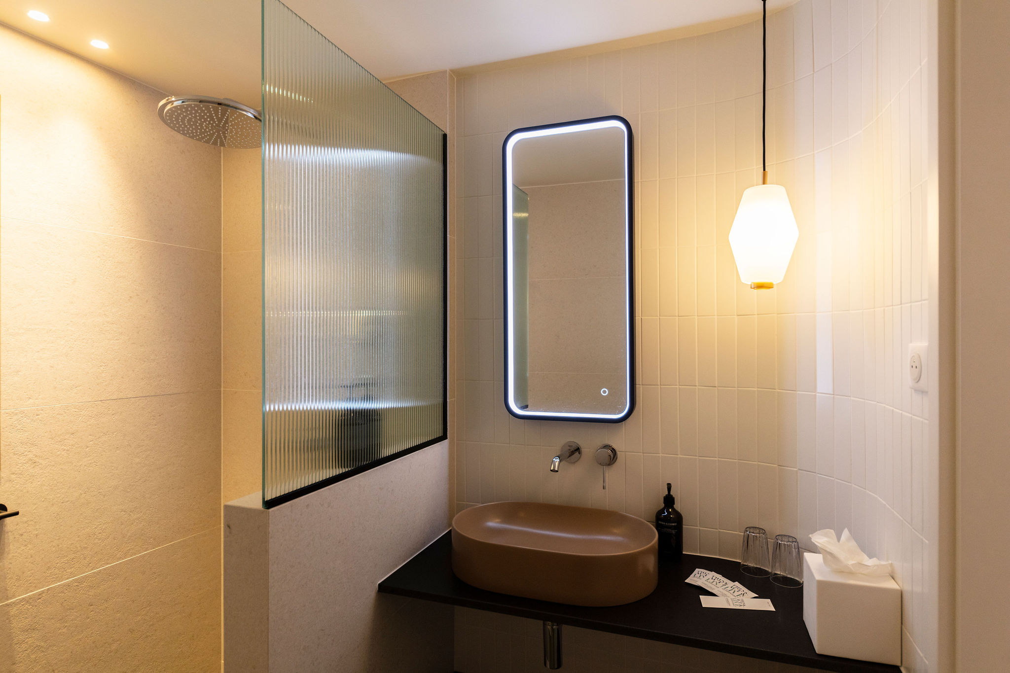 image Brown sink with a modern faucet, backlit styling, and a glass shower partition in the bathroom