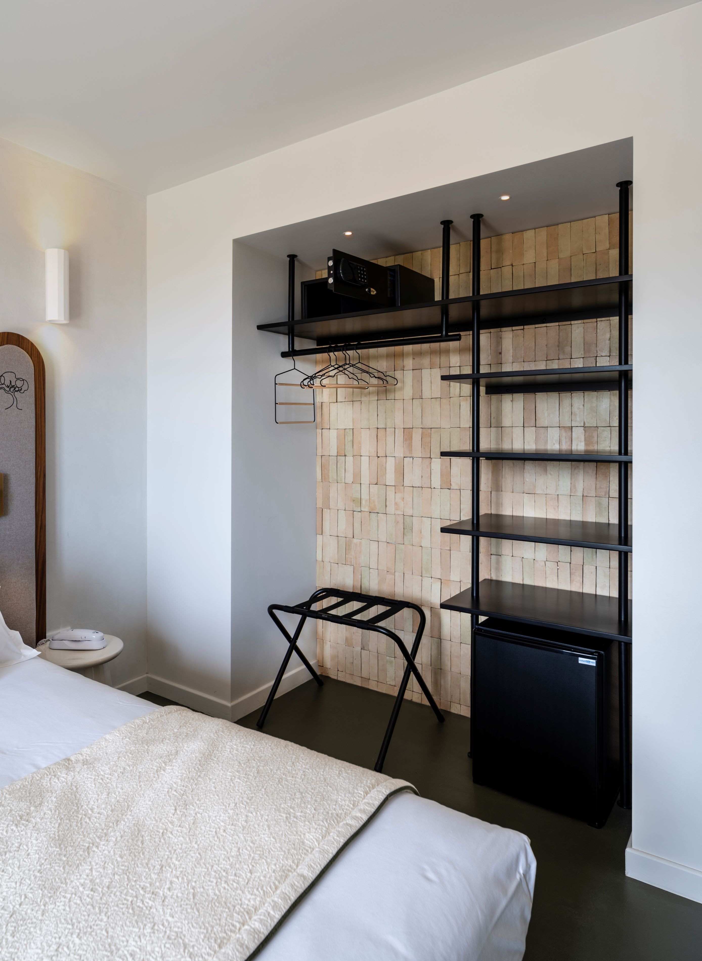 image Storage corner with the minibar fridge and clothes hangers set into light wooden wall panels