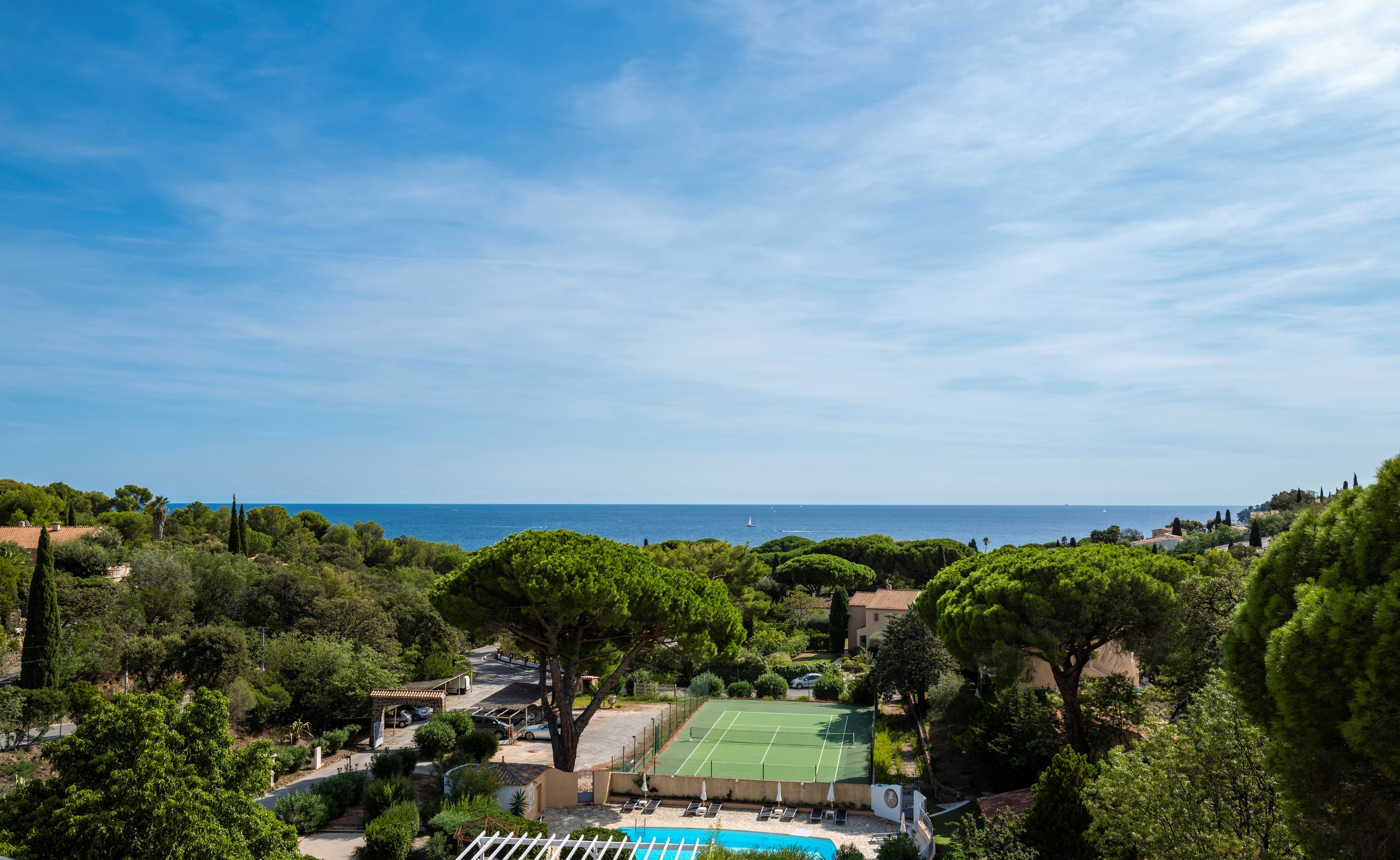 image Balcony view across the park — tennis court below and the sea visible on the horizon