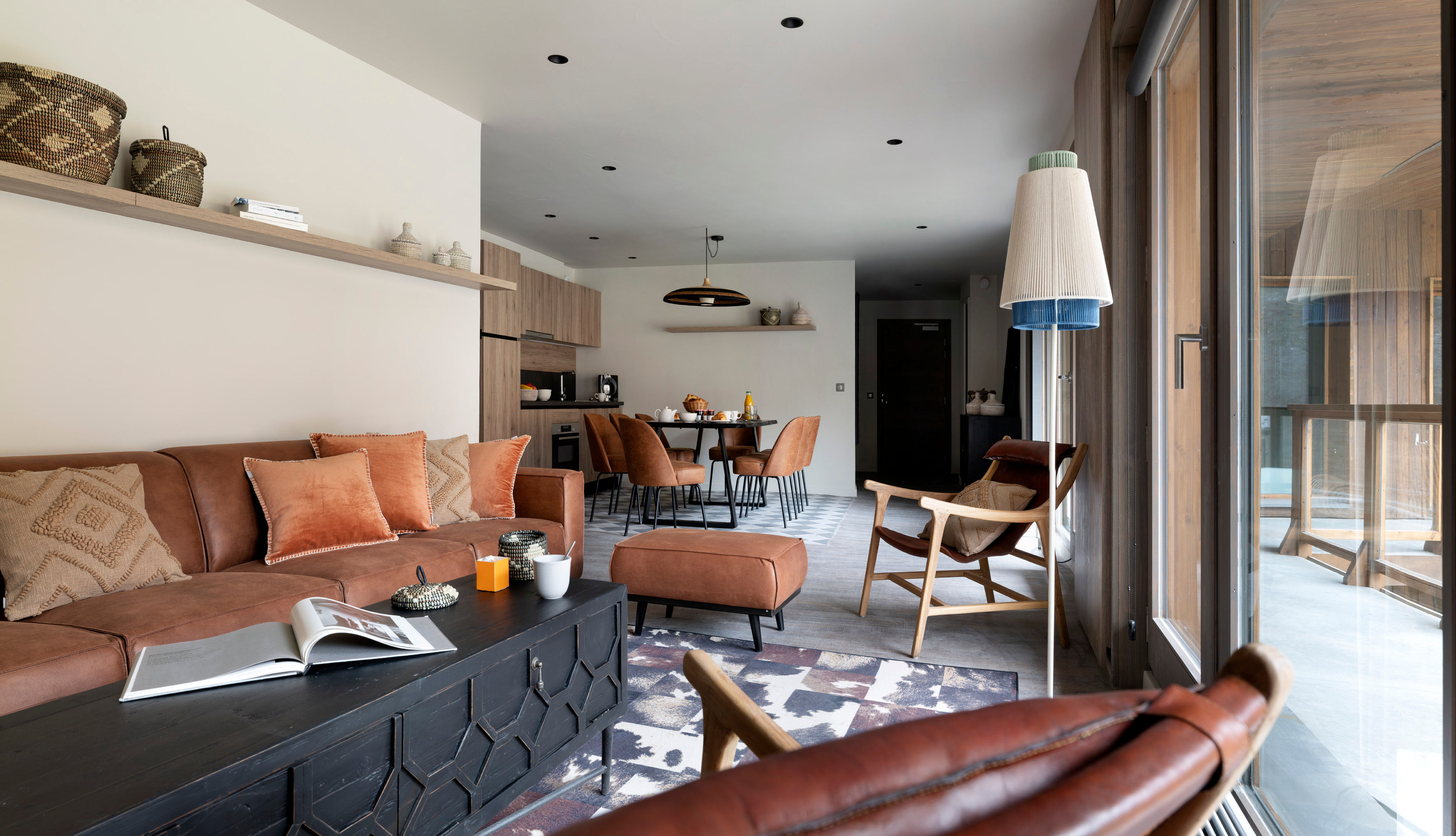 image Brown leather sectional sofa, black coffee table, and layered cushions in the main living area