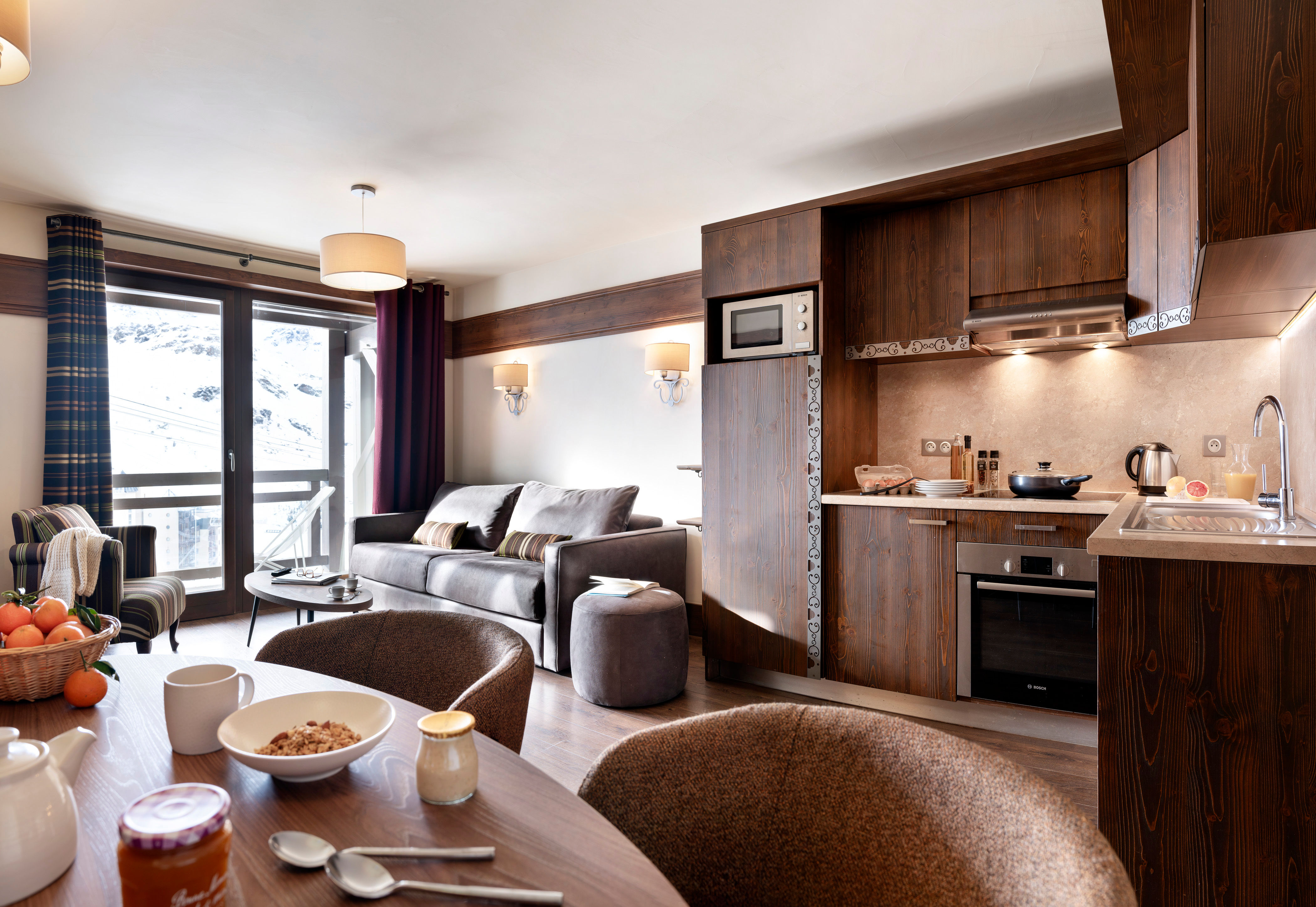 image Fully equipped kitchen with dark wood cabinetry, ceramic hob, and dining table — everything you need for self-catering evenings at 2,300m.