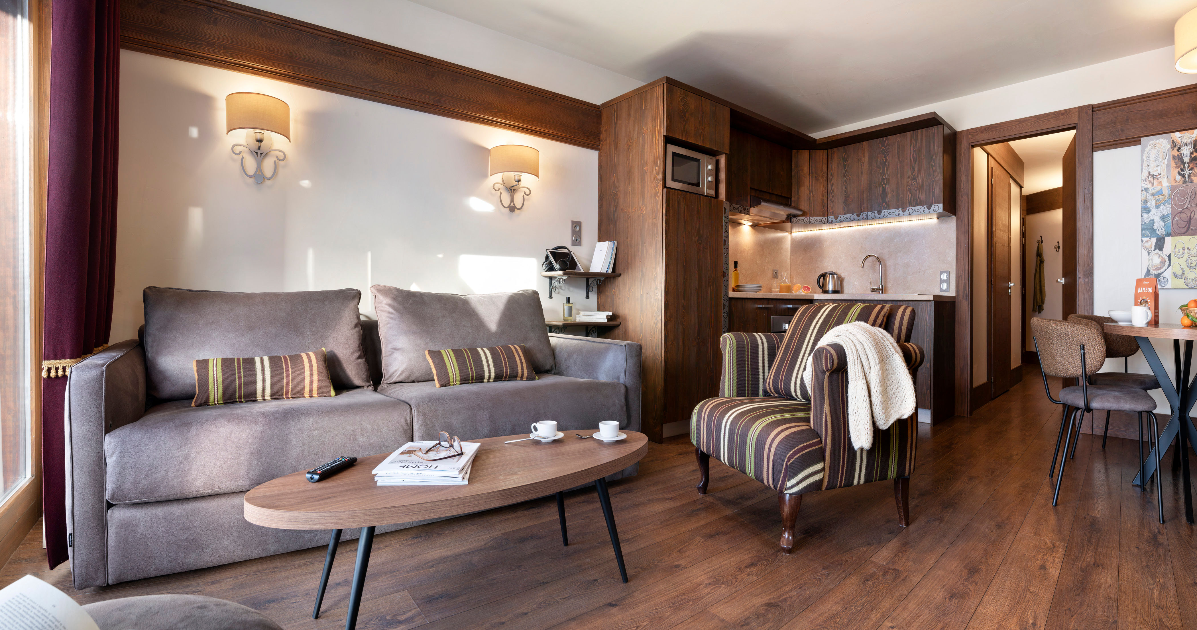 image Open-plan lounge with grey sofa, striped cushions, and warm wood floors — settle in after a day of hiking in the Belleville Valley.