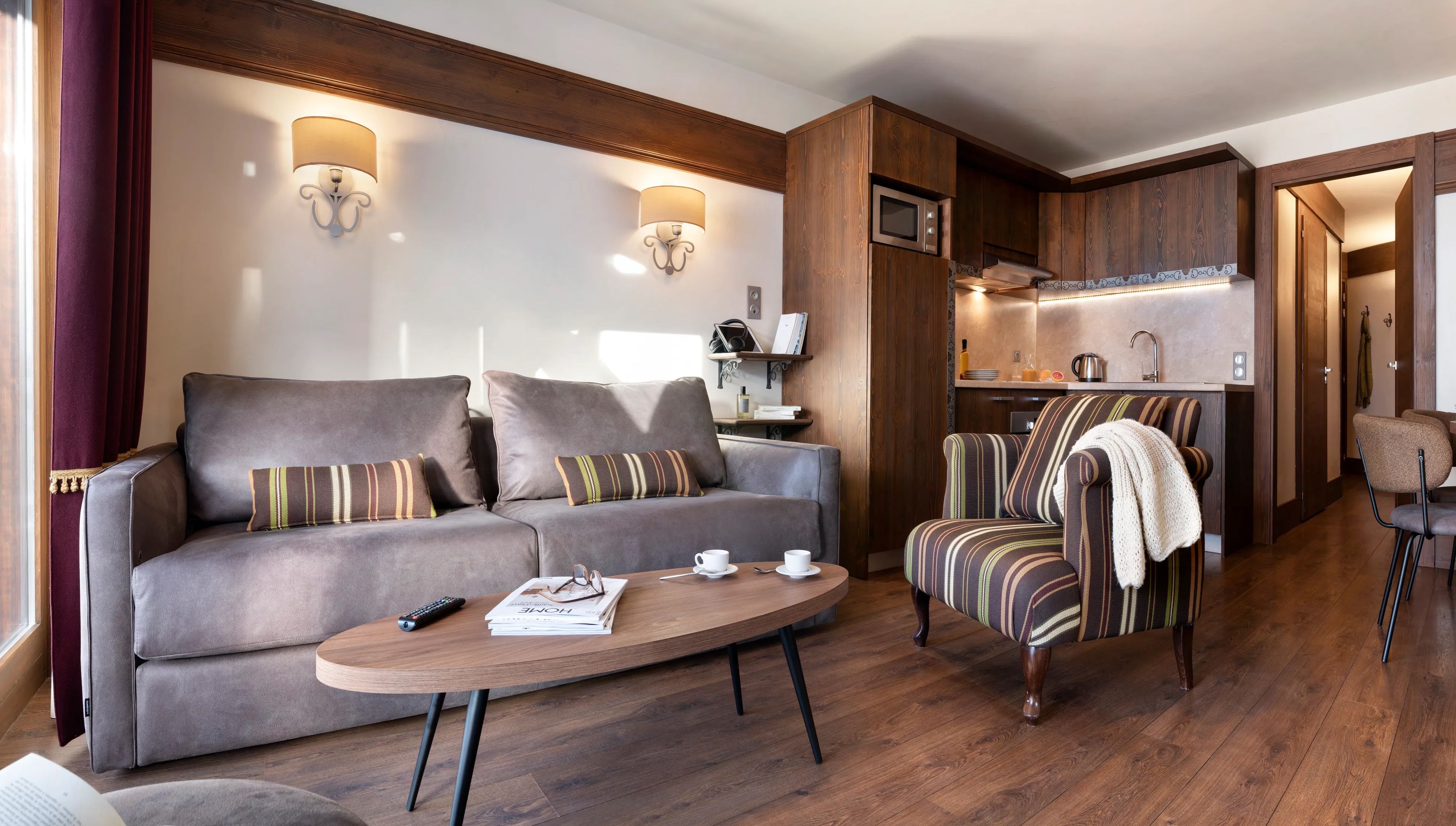 image Open-plan lounge with grey sofa, striped cushions, and warm wood floors — settle in after a day of hiking in the Belleville Valley.