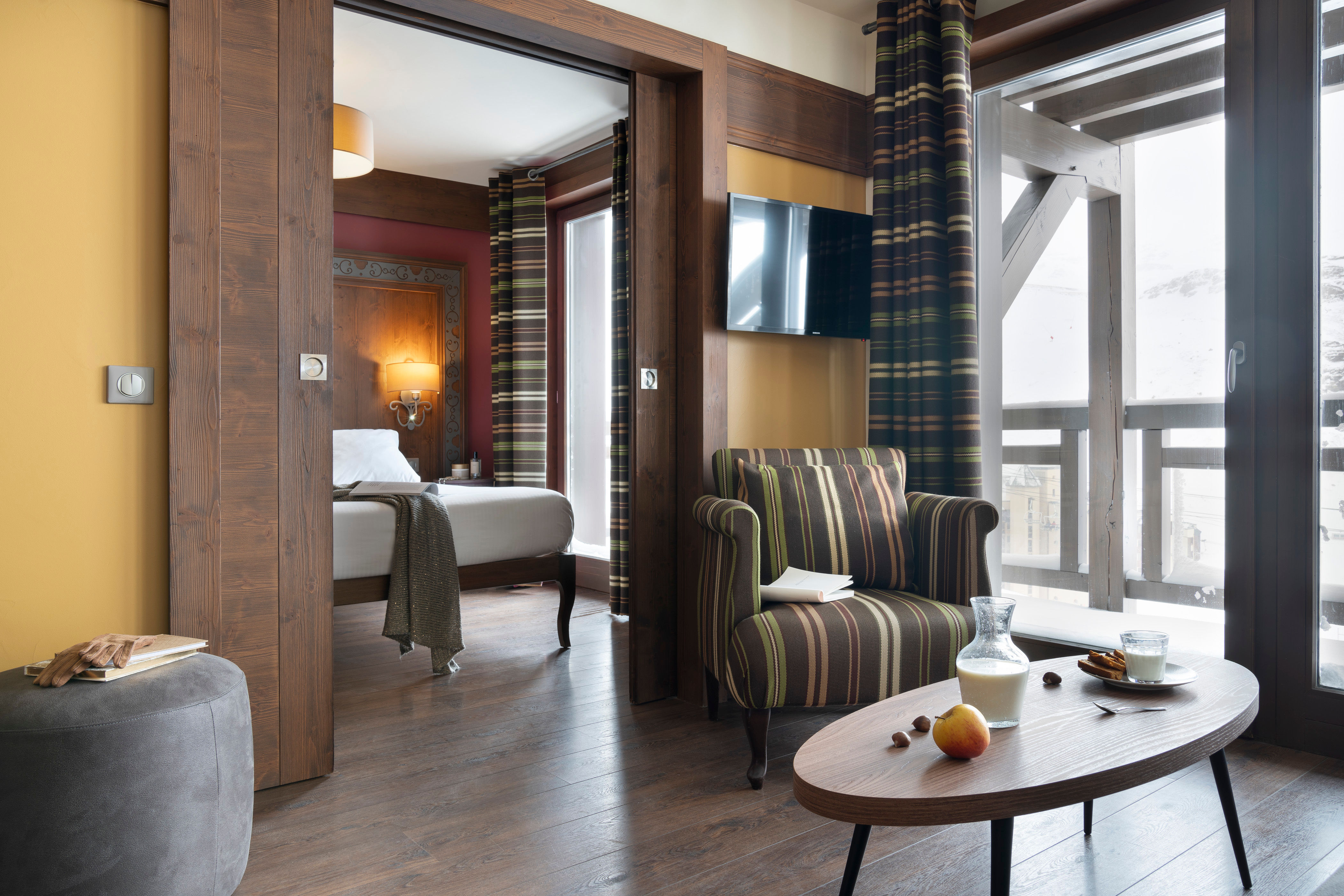 image The lounge opens directly onto the balcony, with a round table and striped armchair framing the mountain light coming through the door.
