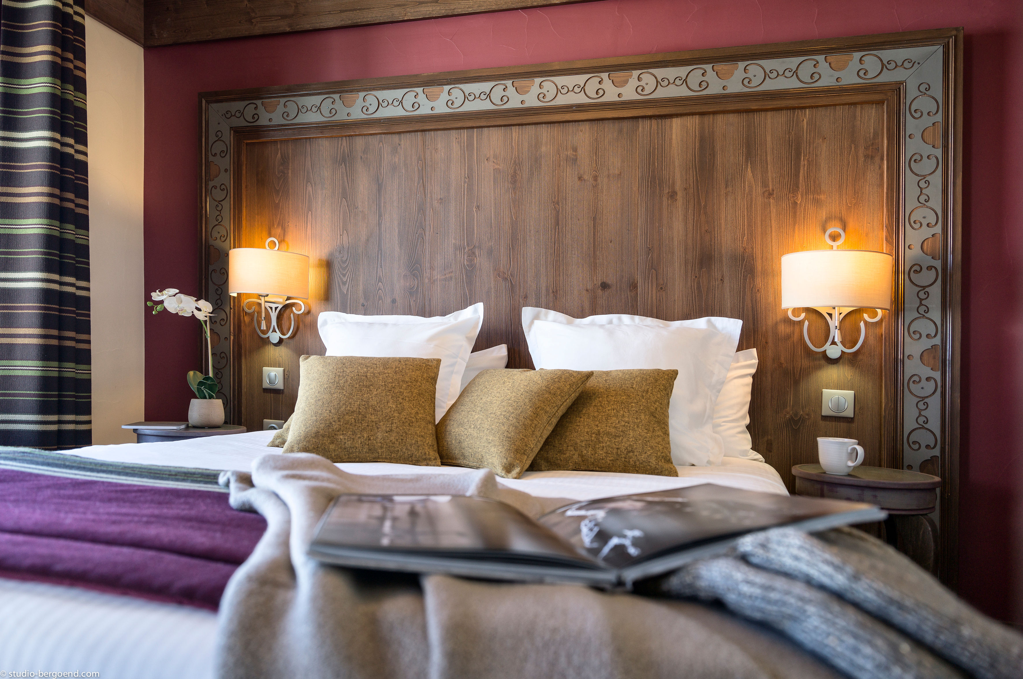 image Double bedroom with an ornate carved headboard, gold cushions, and deep red accent wall — beds made up fresh for your arrival.
