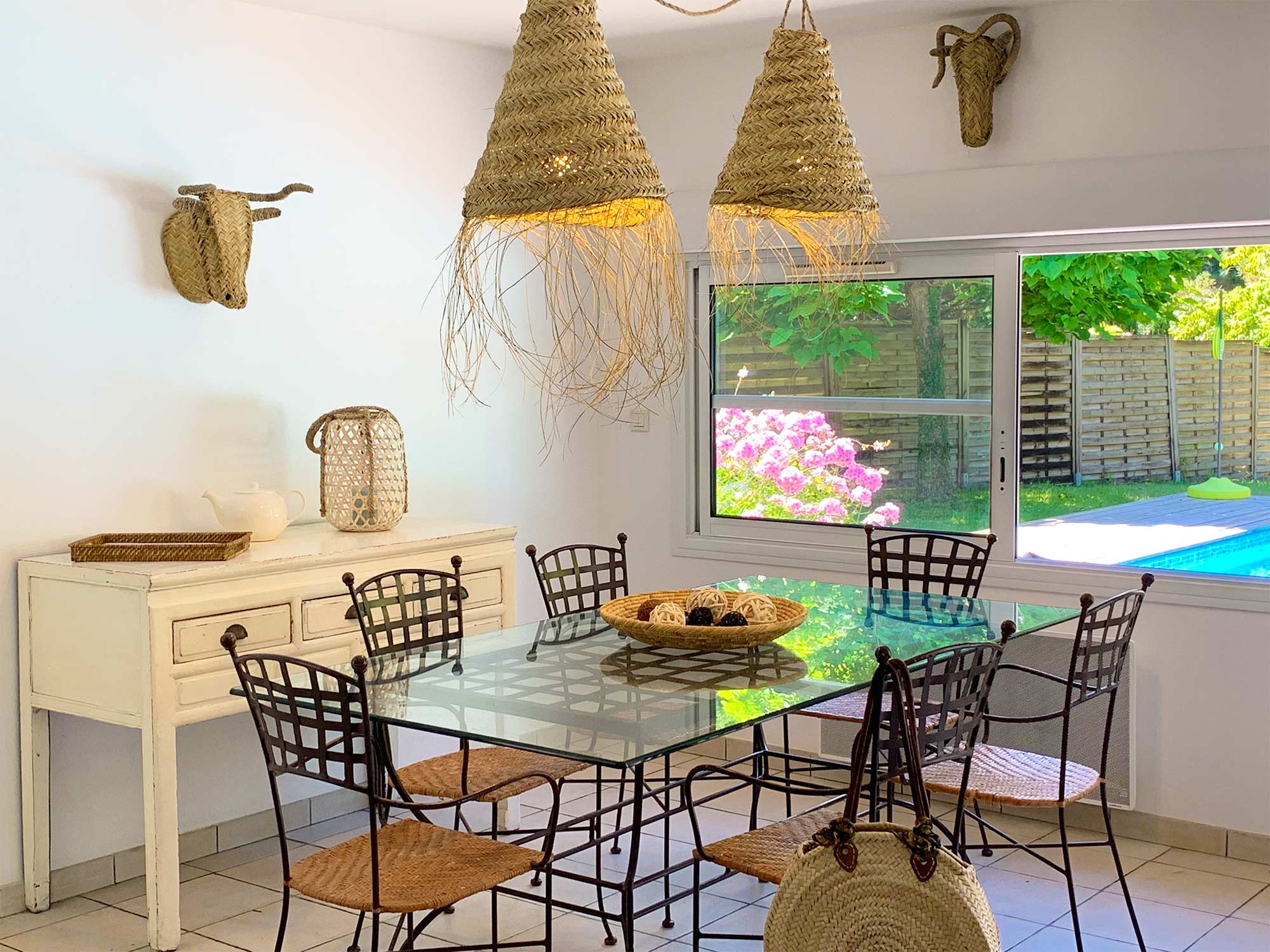 image Rattan pendant lights over a glass dining table, with the pool and garden visible through the terrace doors.