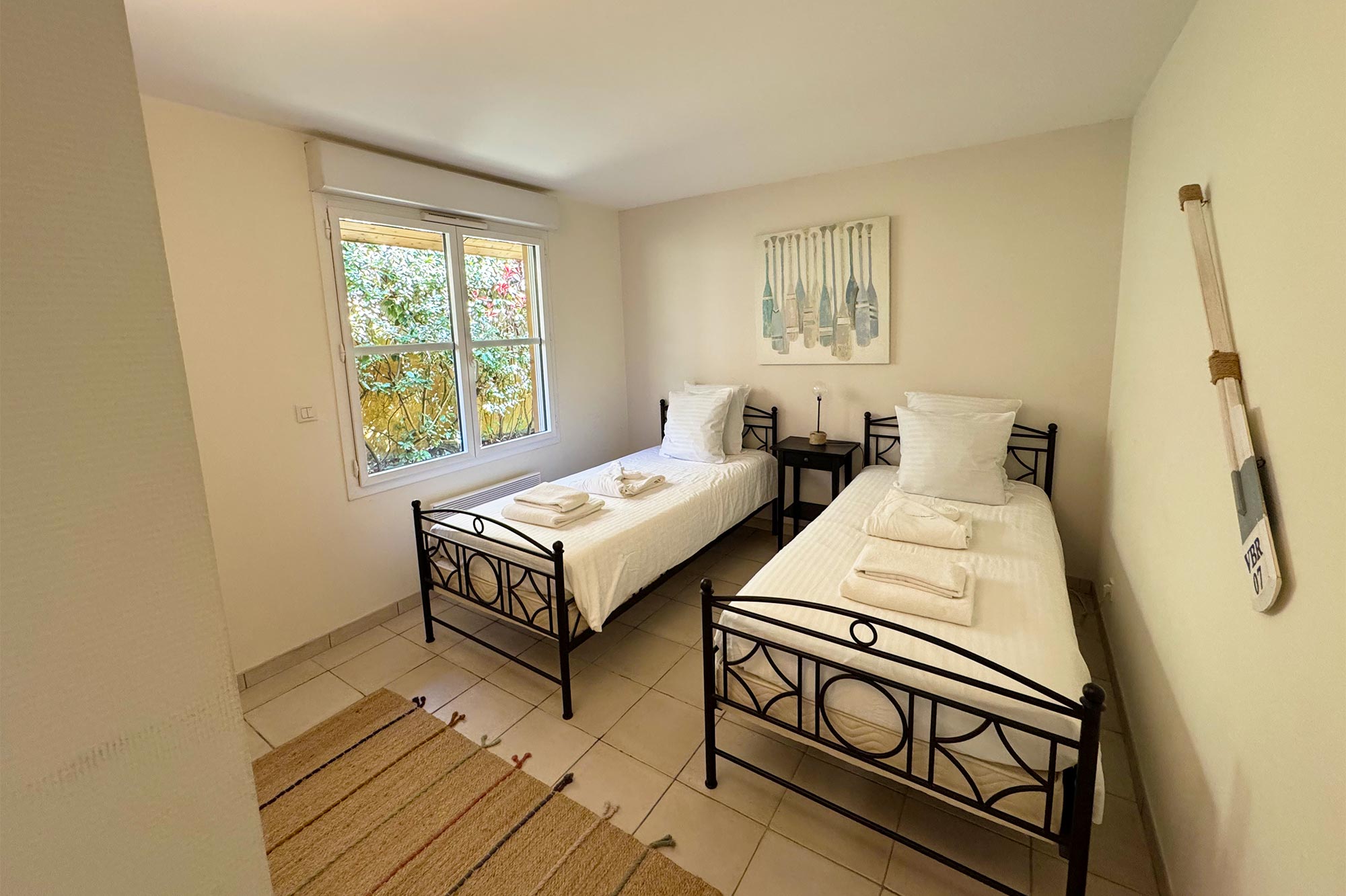 image Iron-frame single bed on a warm wooden floor — bright room with a garden-facing window and plenty of natural light.