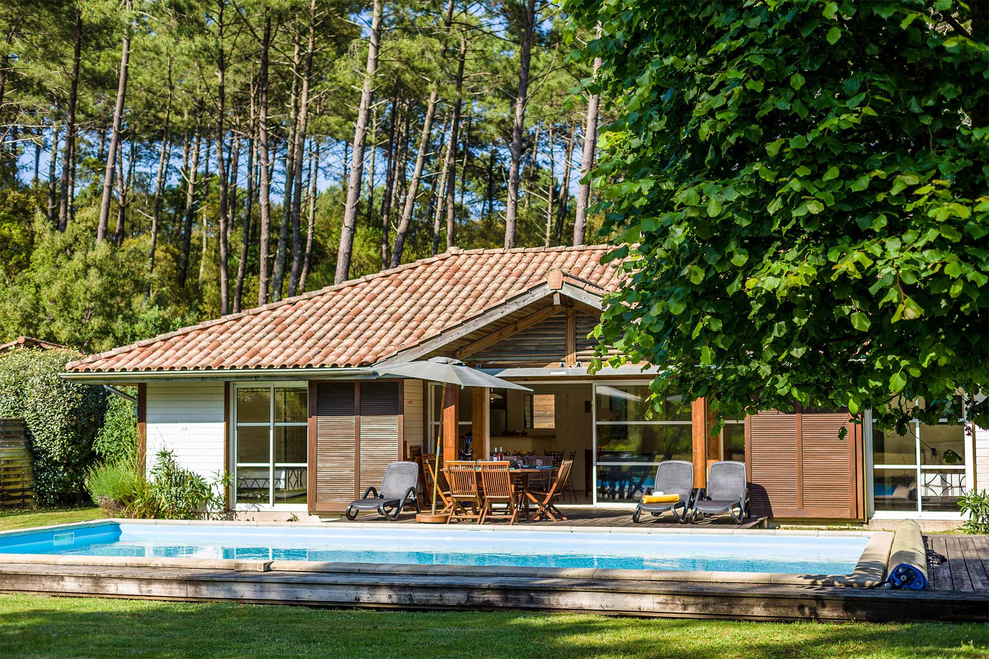 image Stone-and-timber villa with a private pool in the garden — tall Landes pines rising behind, the lake a short walk away.