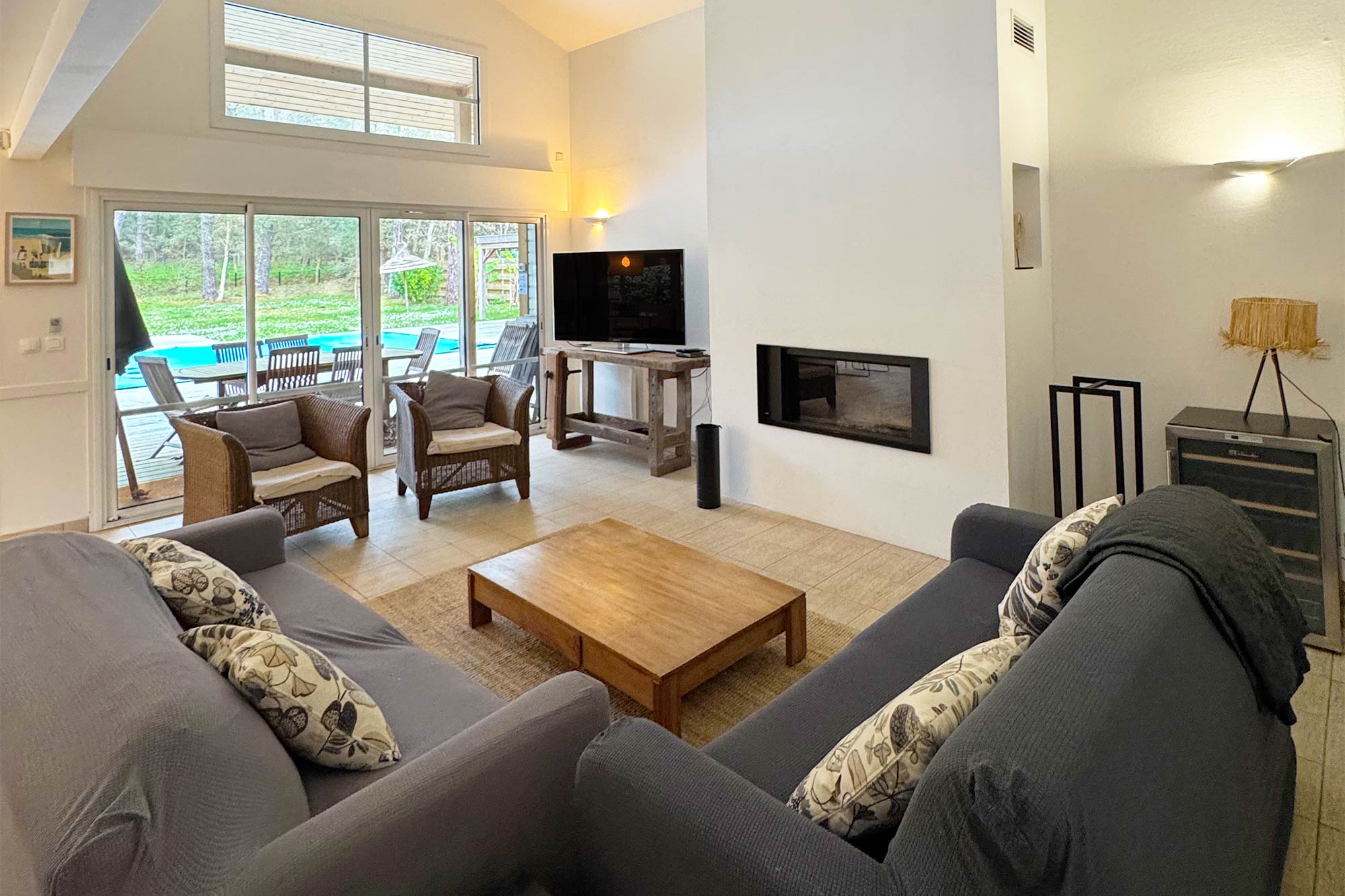 image Spacious living room with a fireplace and wooden coffee table — direct access to the garden and pool just beyond the glass doors.