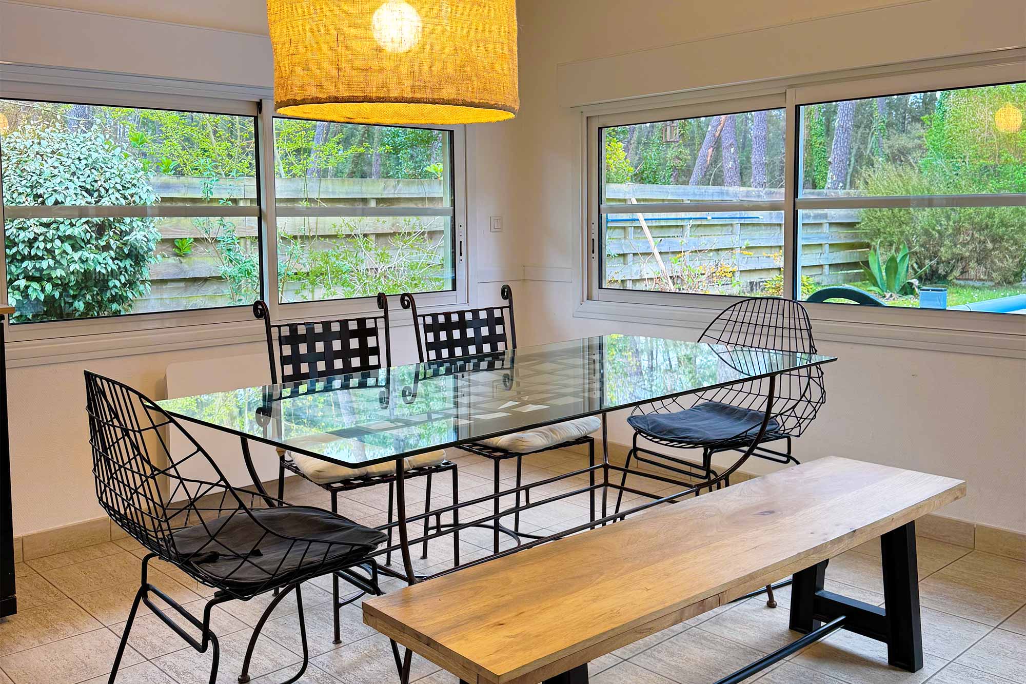 image The dining table sits under a rattan pendant light, floor-to-ceiling windows bringing the pine forest garden right to the table.
