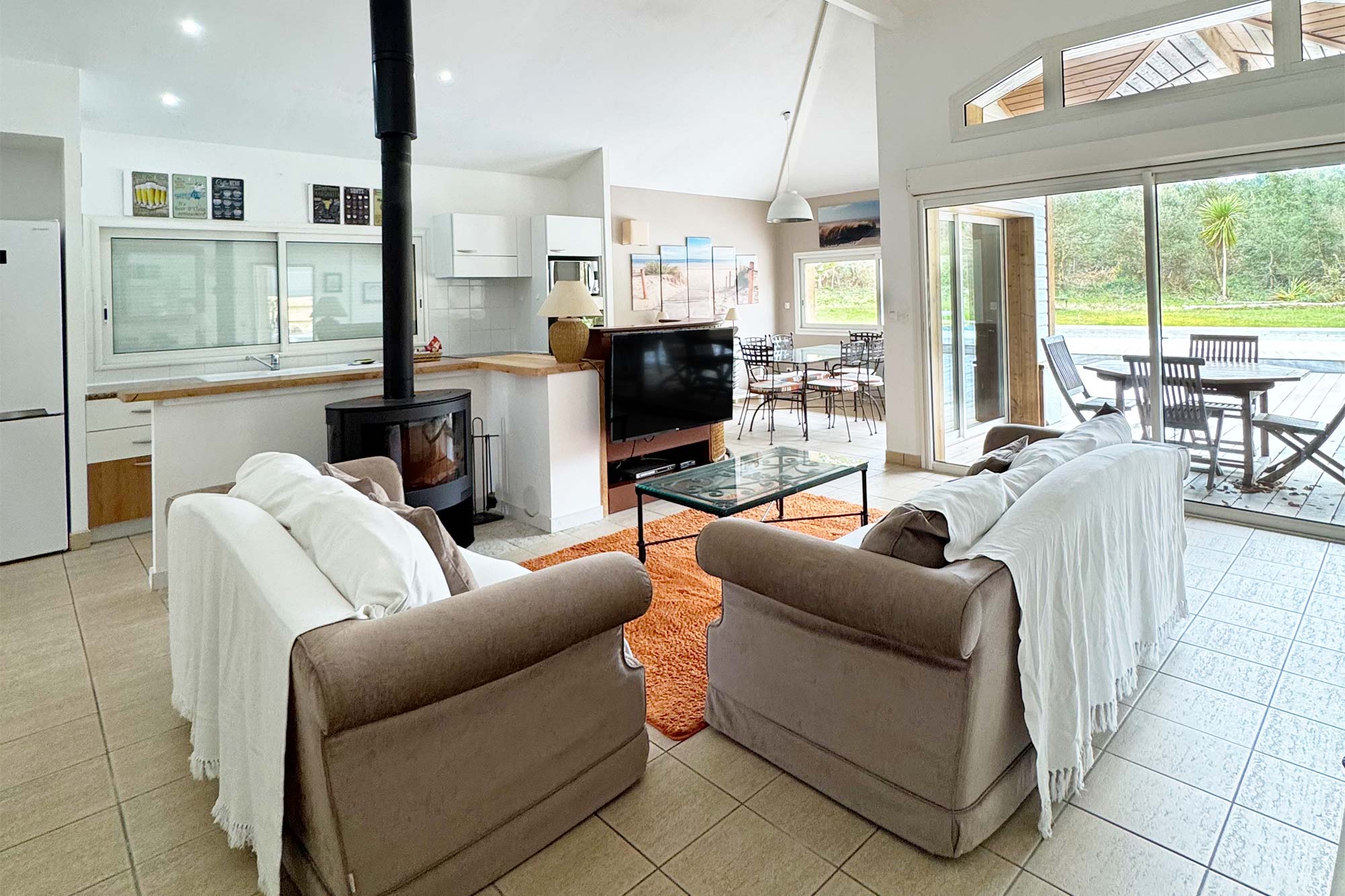 image Open-plan living area, kitchen visible in background, sofa, tiled floors, bright space:
The bright open-plan living and kitchen area sets the tone — fully renovated and ready to welcome your whole group.