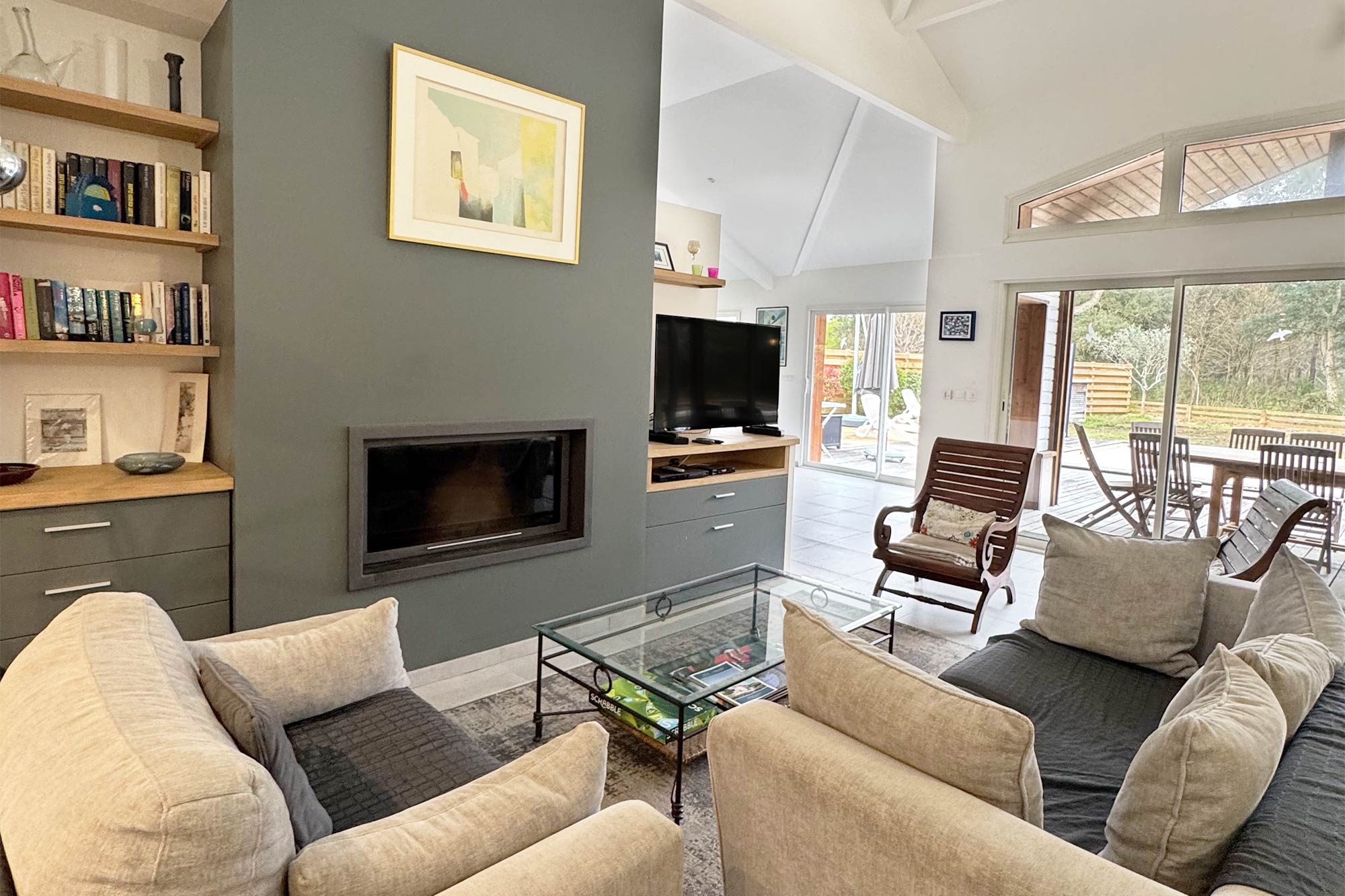 image Living room, fireplace, grey sofas, high ceilings, large windows, natural light:
The spacious living room features high ceilings, a fireplace, and generous natural light — a refined space to unwind after a day at the beach or on the golf course.