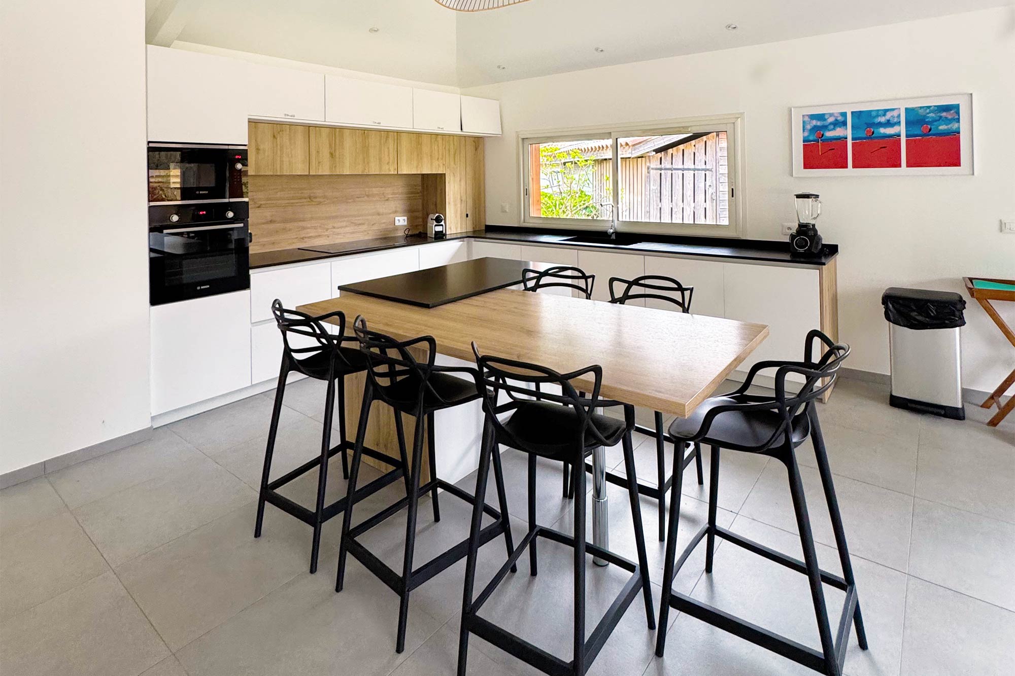 image Open-plan kitchen, island with bar stools, modern fittings, colourful canvas above:
The large open-plan kitchen is one of this villa's standout features — sleek, fully equipped, and designed for groups who love to cook and gather together.