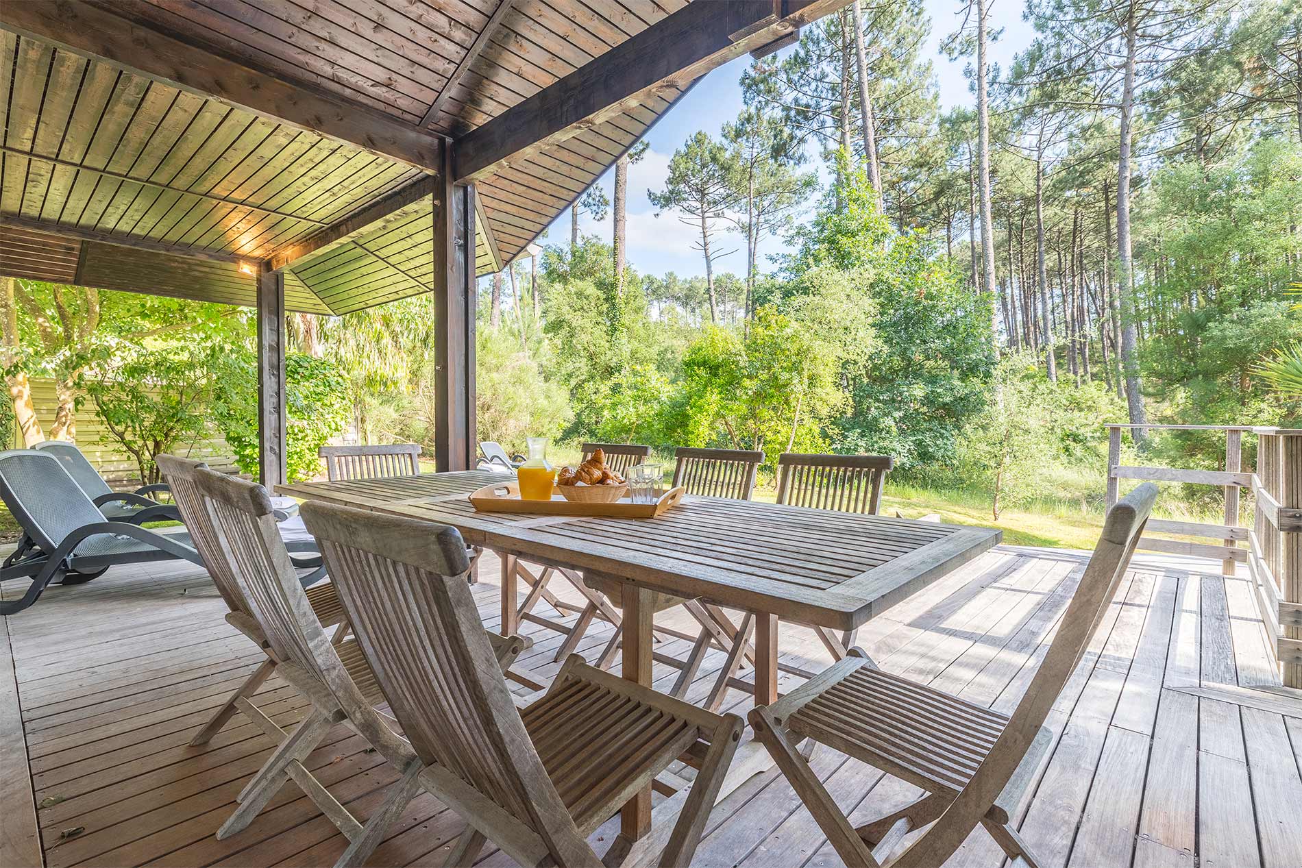 image Covered terrace with large wooden dining table, forest views all around, pine trees:
Dine al fresco under the covered terrace, surrounded by the sights and sounds of the Landes forest — the perfect setting for long summer evenings.