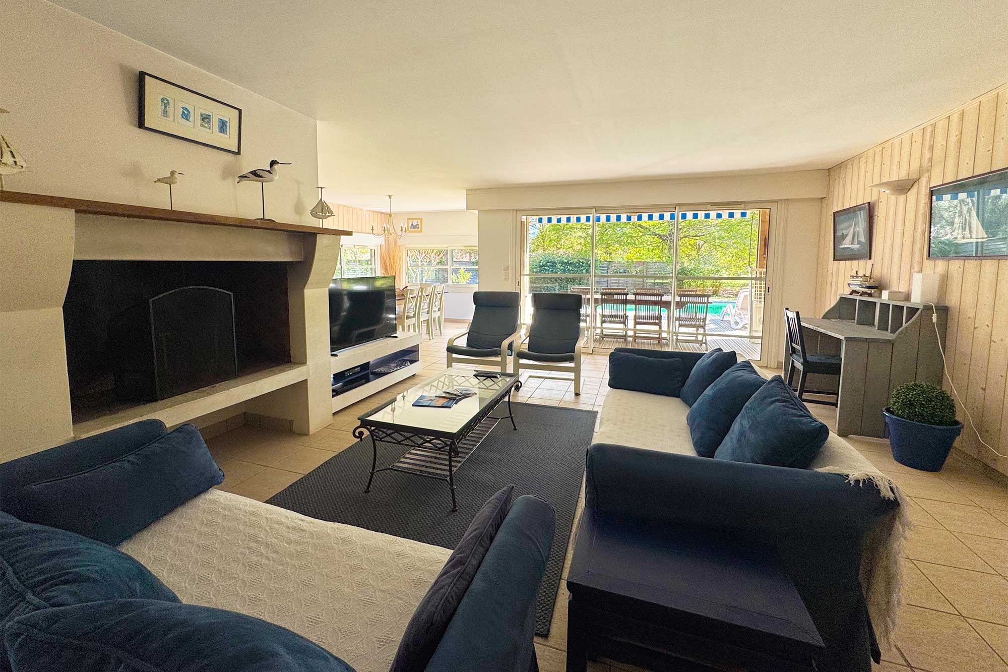 image Open-plan living room with plush sofas and a fireplace — high ceilings and light-wood floors throughout.