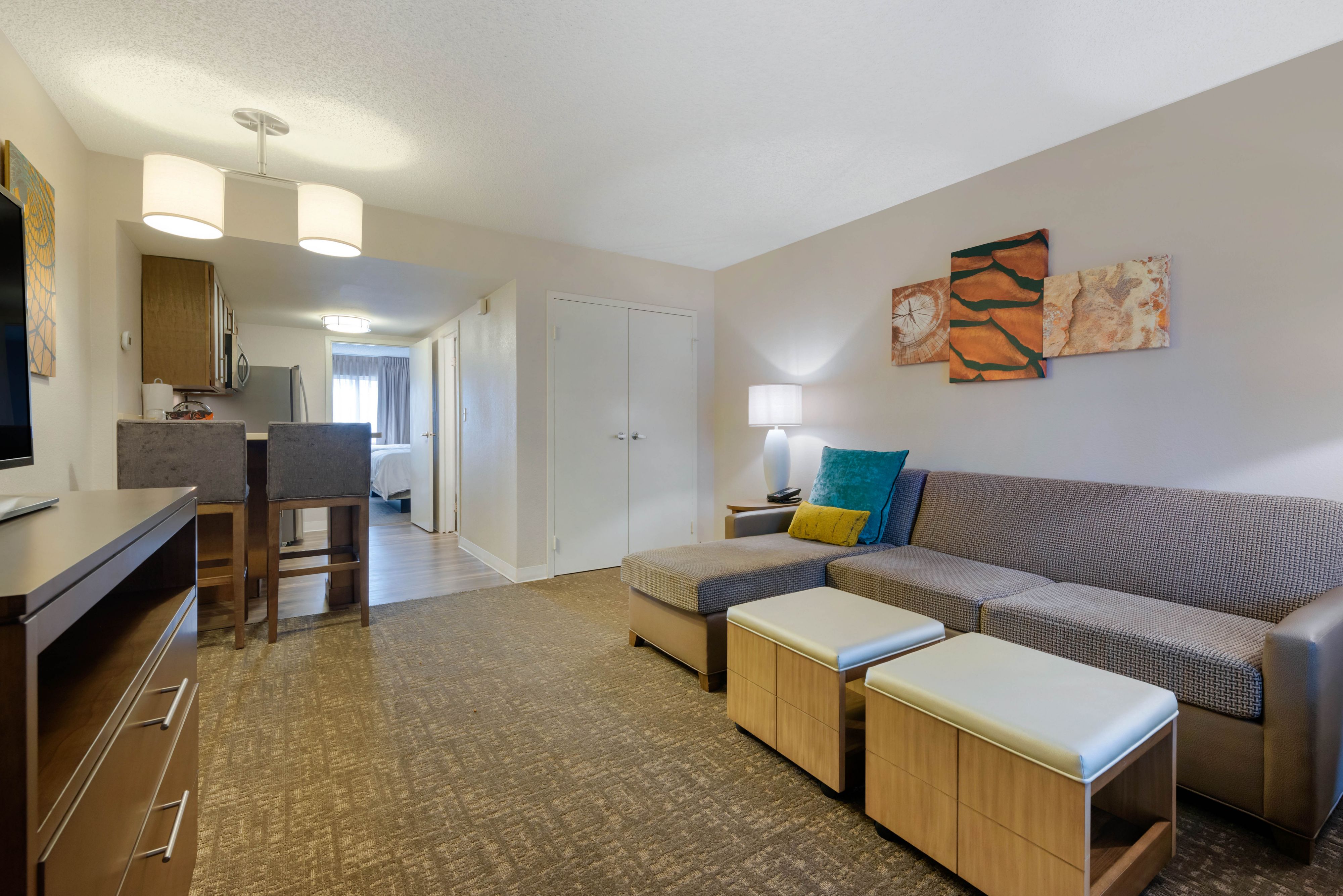 image Living area with sofa, bar stools, and kitchen counter.