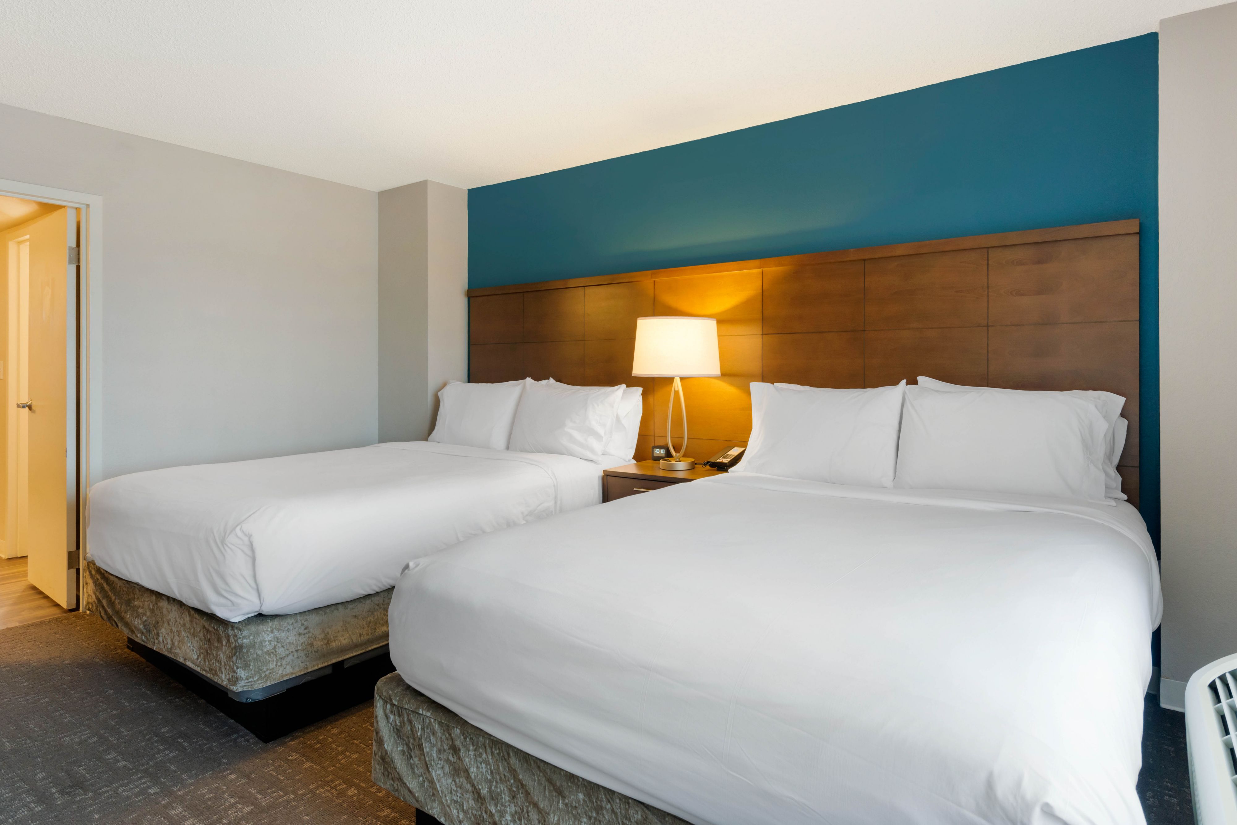 image Spacious bedroom with two neatly made beds and a lamp.