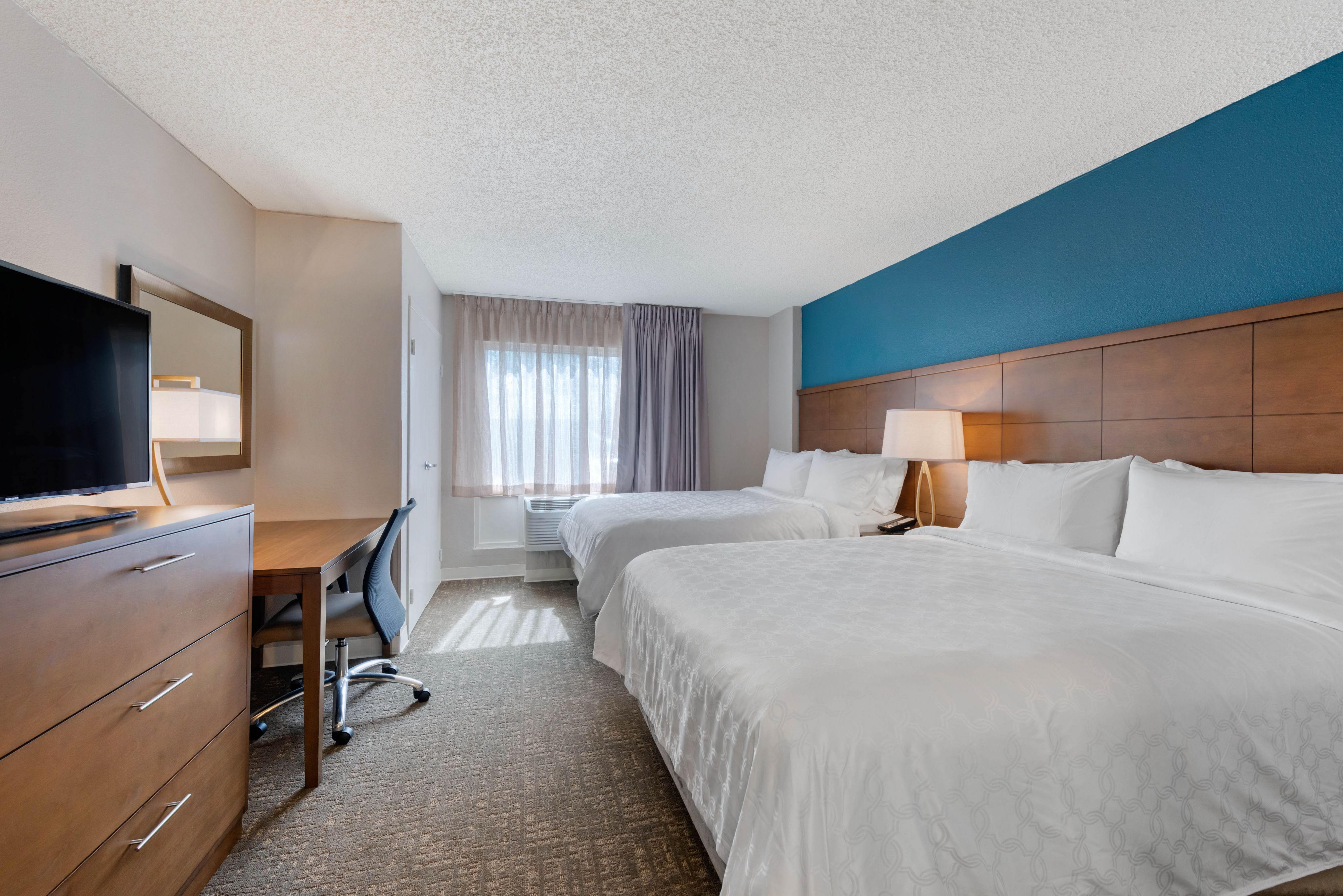 image Bright bedroom featuring two large beds and natural light.