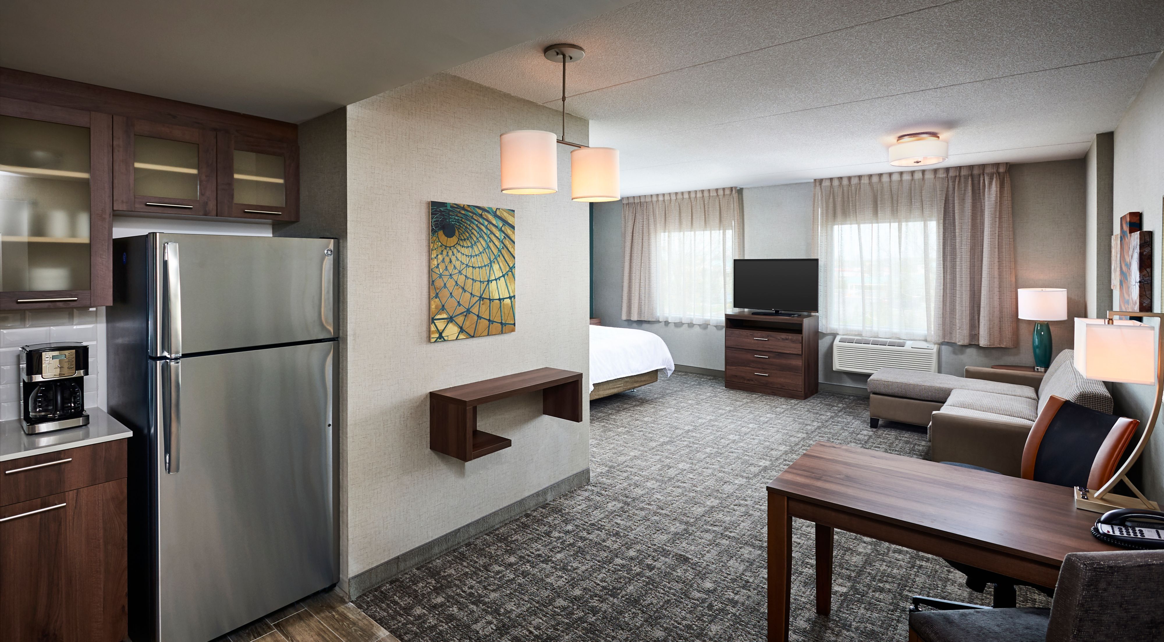 image Suite living area with TV, desk, refrigerator, and seating.