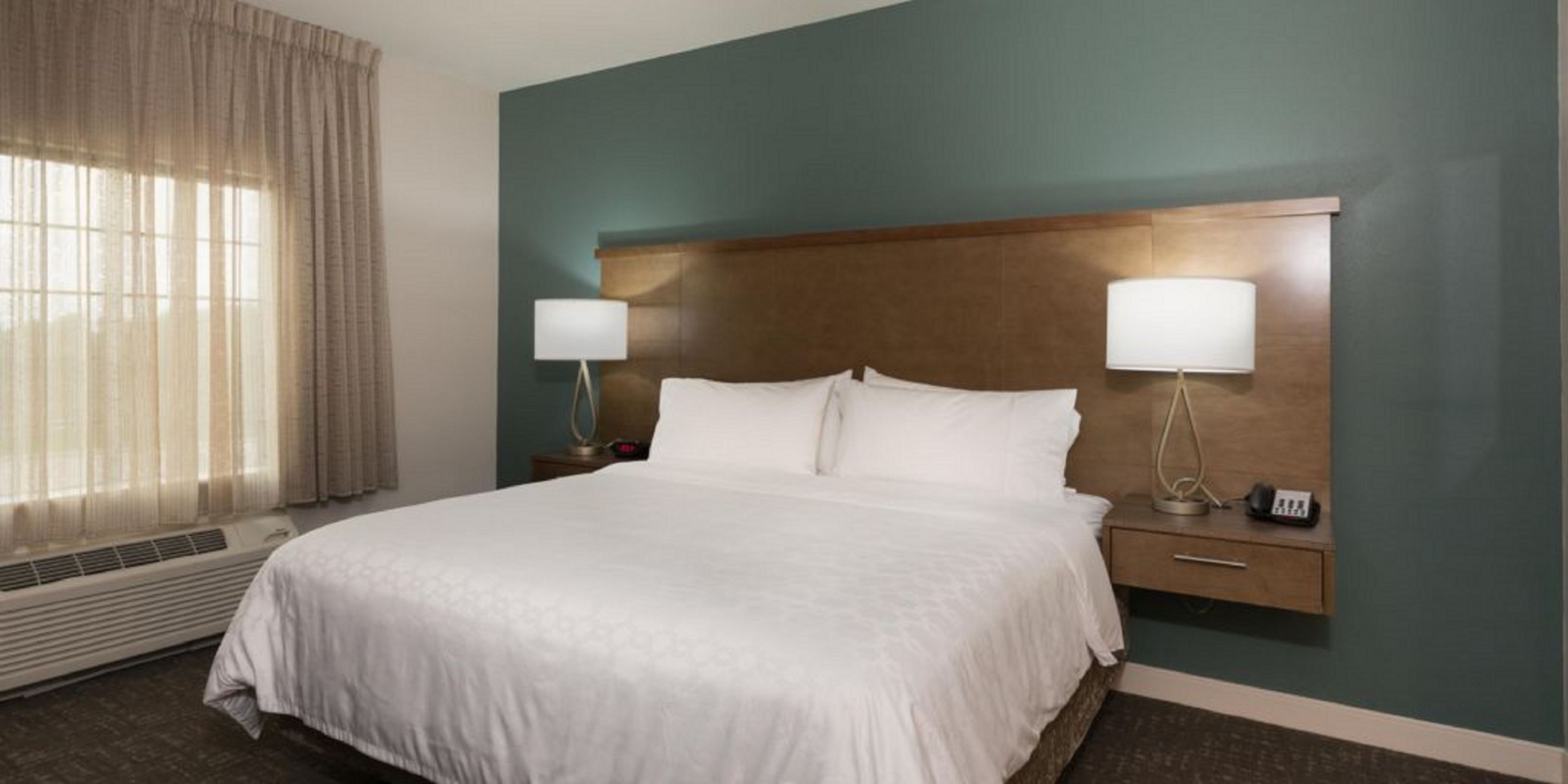 image Rest easy in a cozy king bed, complemented by warm lighting and soft drapes for a peaceful retreat.