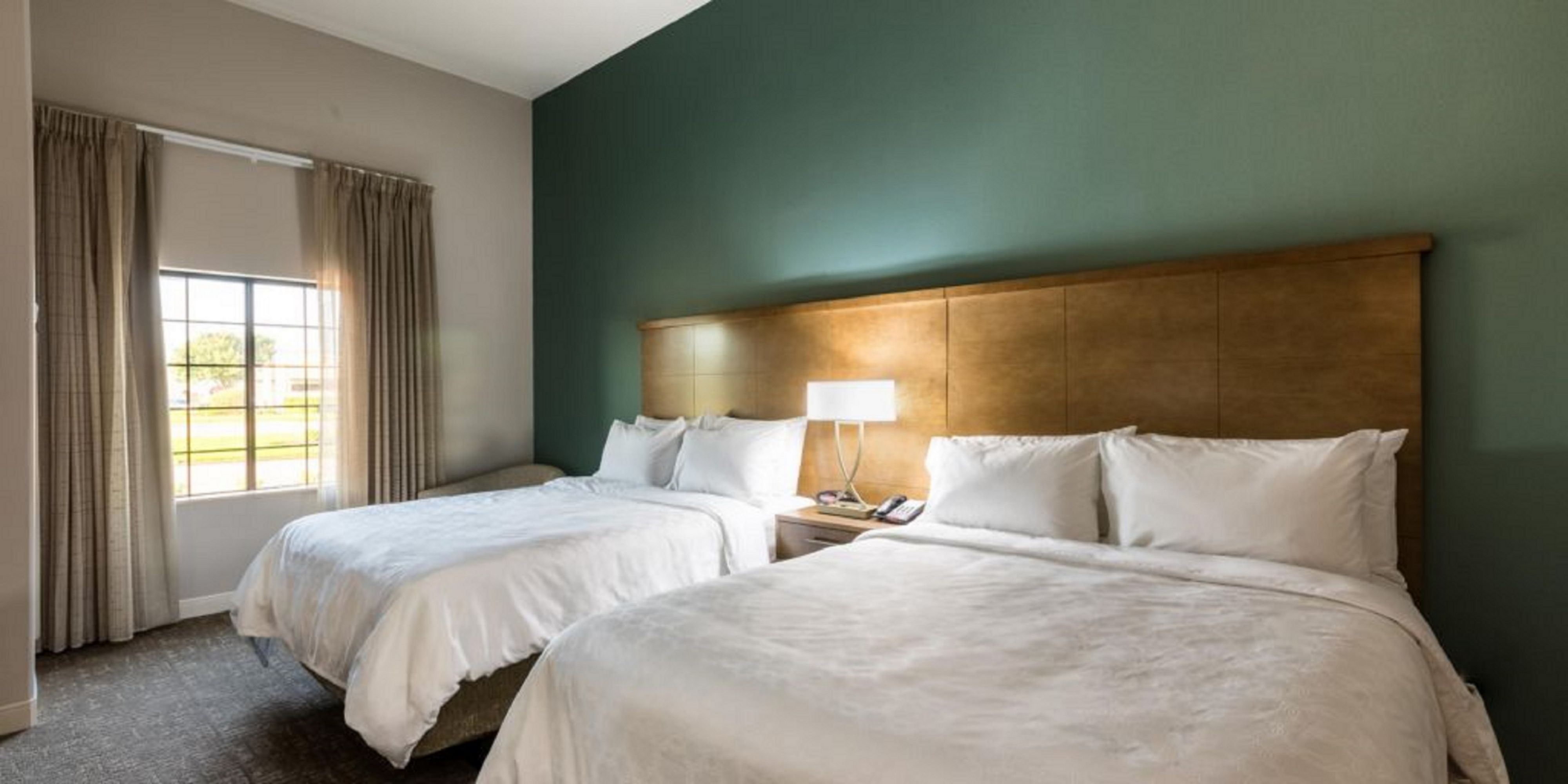 image Sleep soundly on plush queen beds, surrounded by serene colors and soft linens for your comfort.