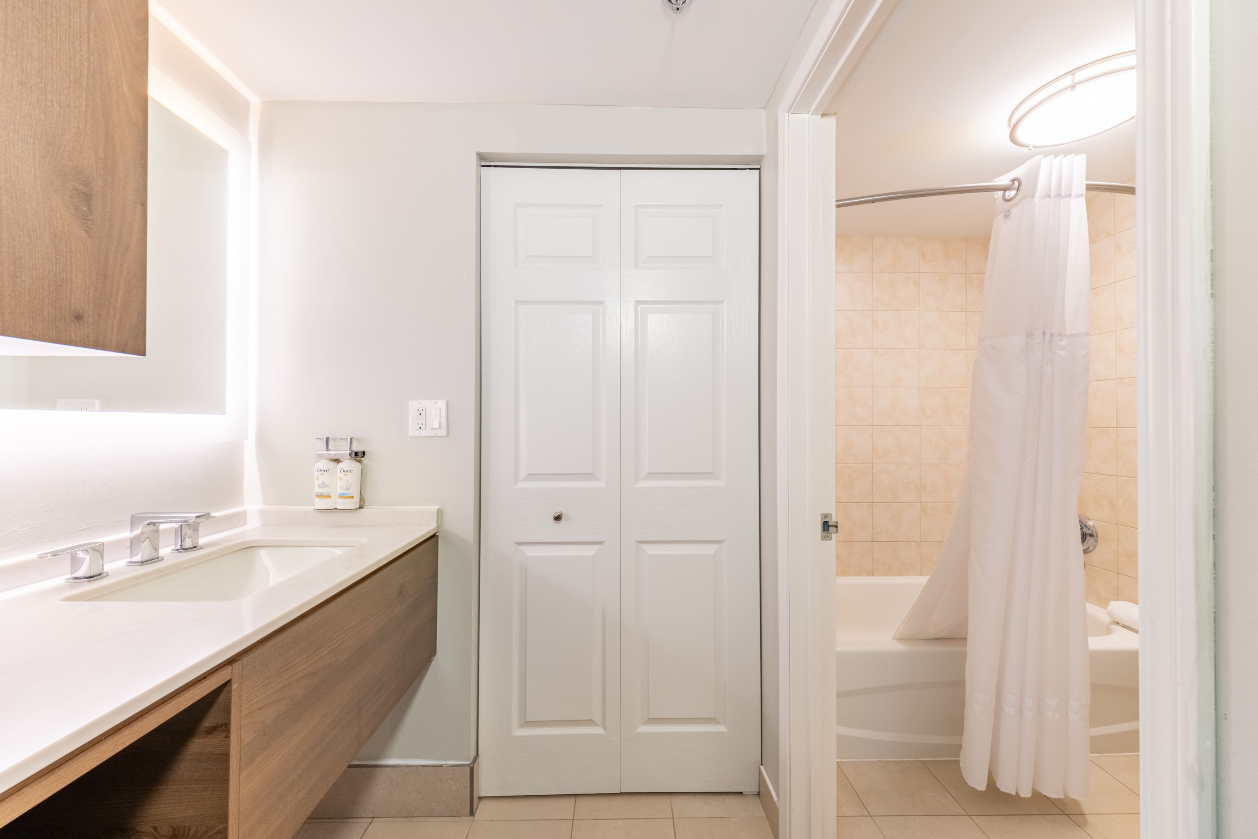 image Bathroom with dual-sink vanity, large countertop, and shower-tub combination.