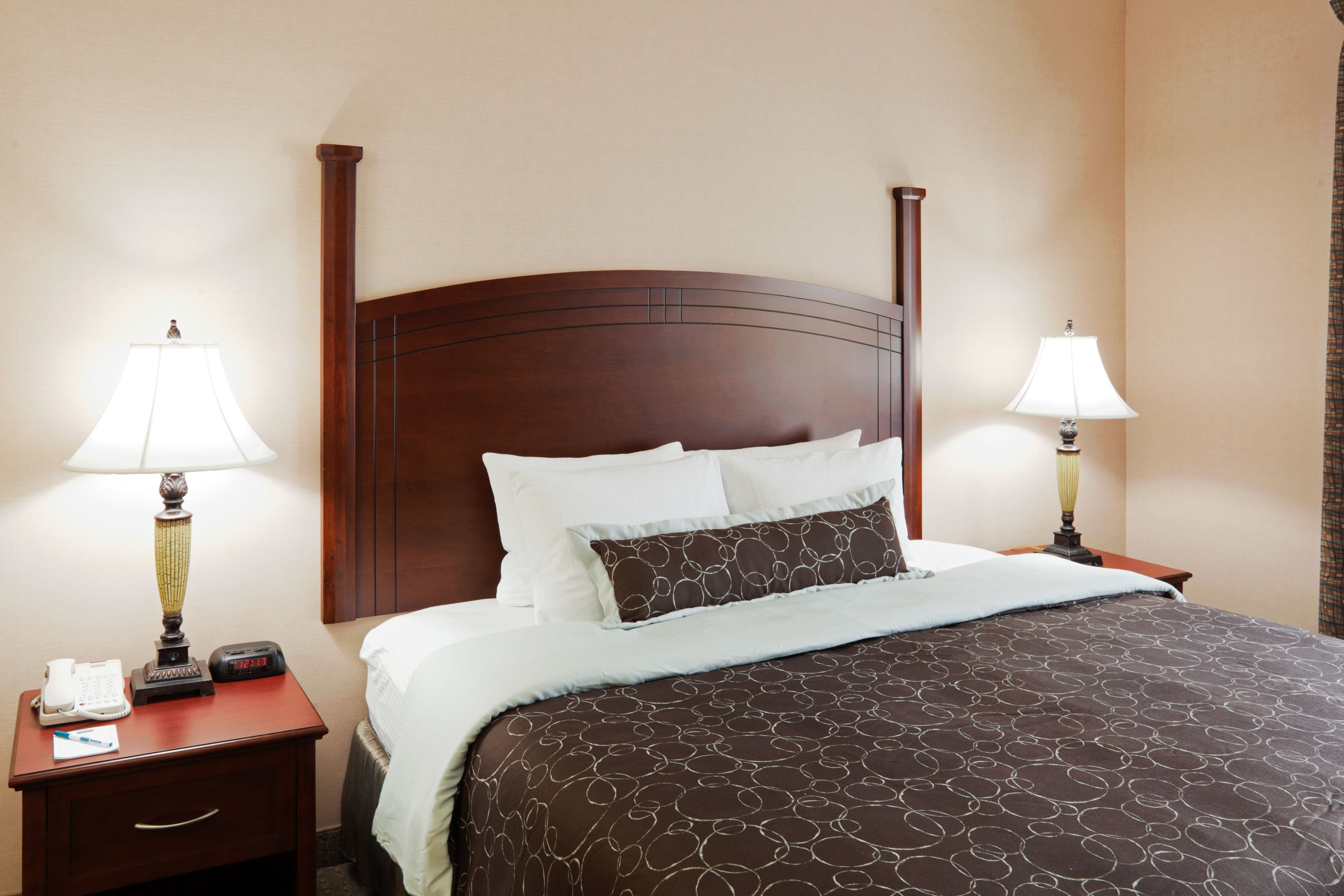 image Queen bed with plush pillows and warm nightstand lighting.