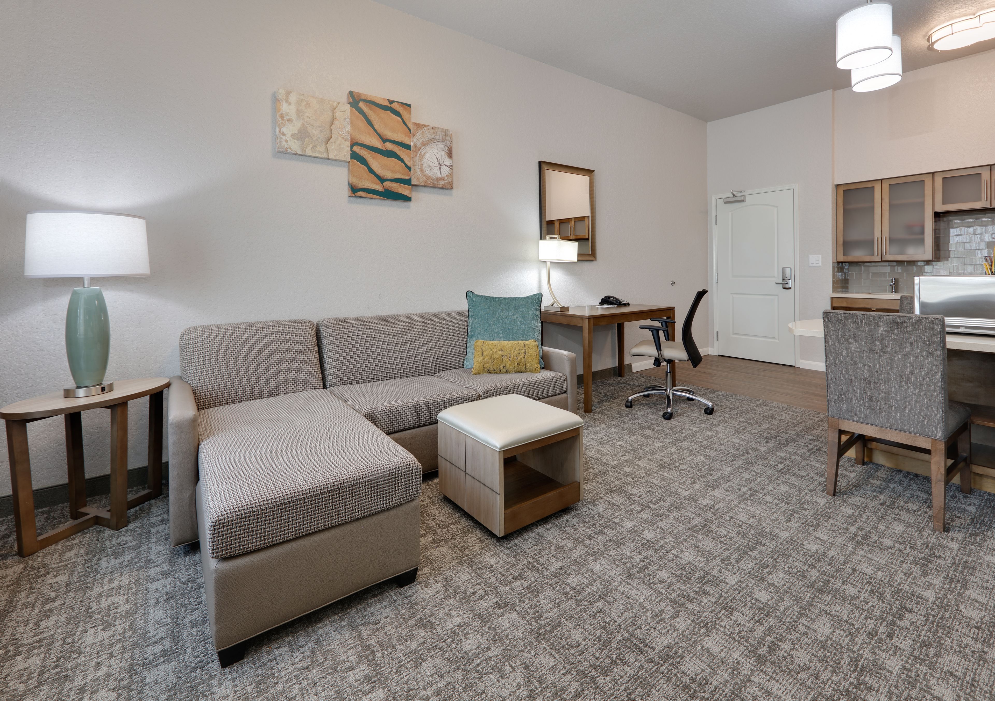 image Open living area with sofa bed, workspace, and adjacent kitchen.