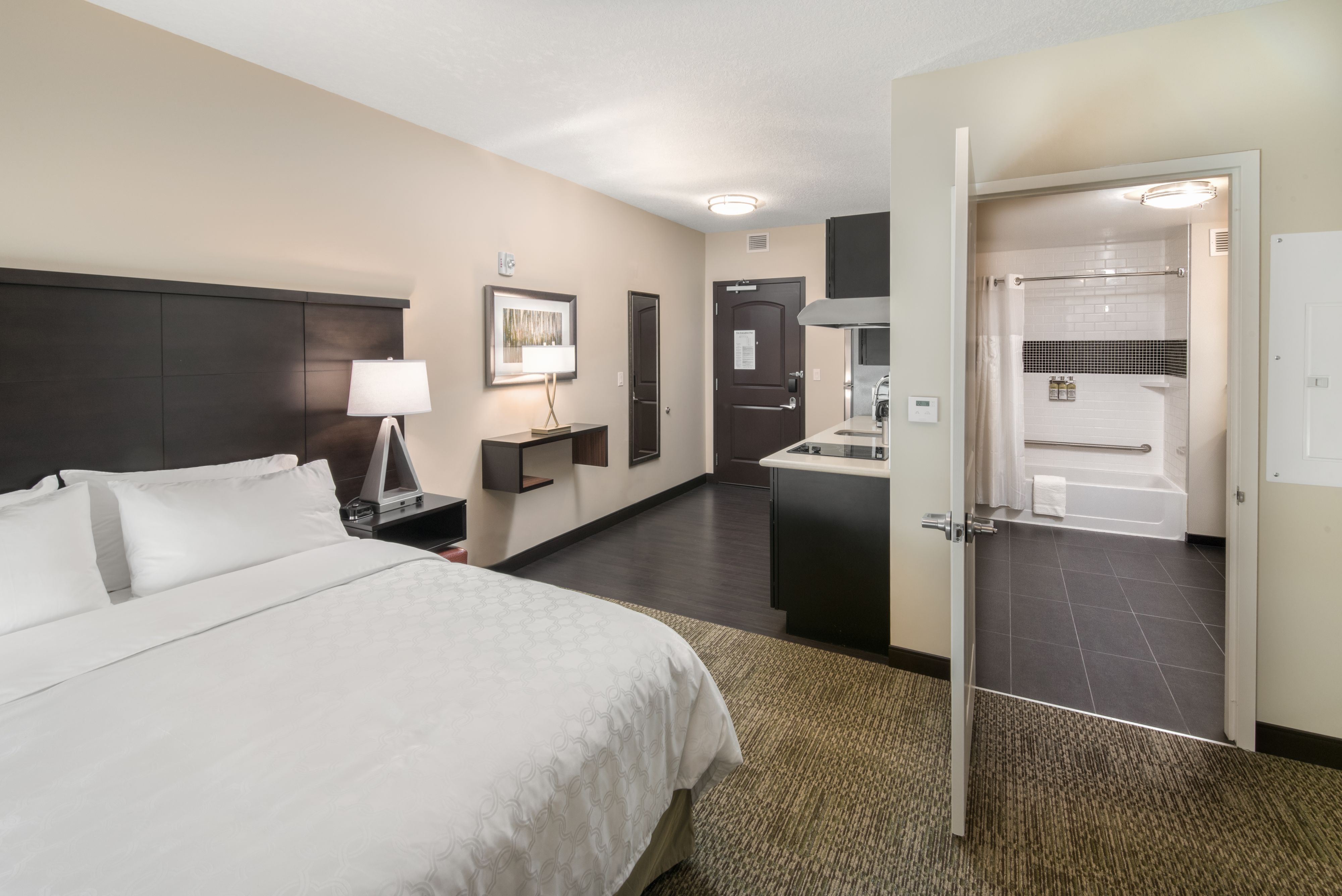 image Studio suite with queen bed, lamp, and kitchen area.
