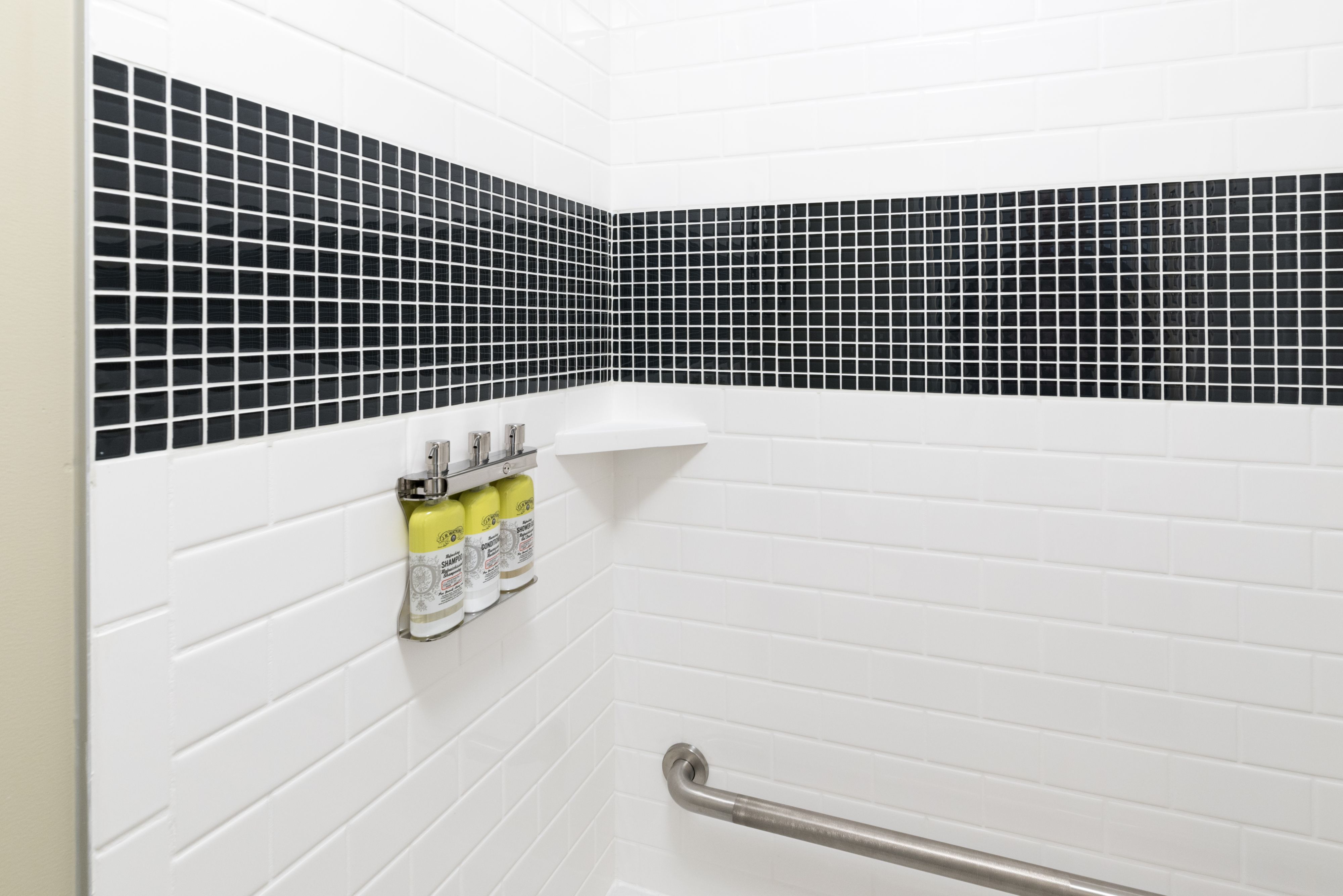 image Tiled shower with built-in dispensers and modern fixtures.