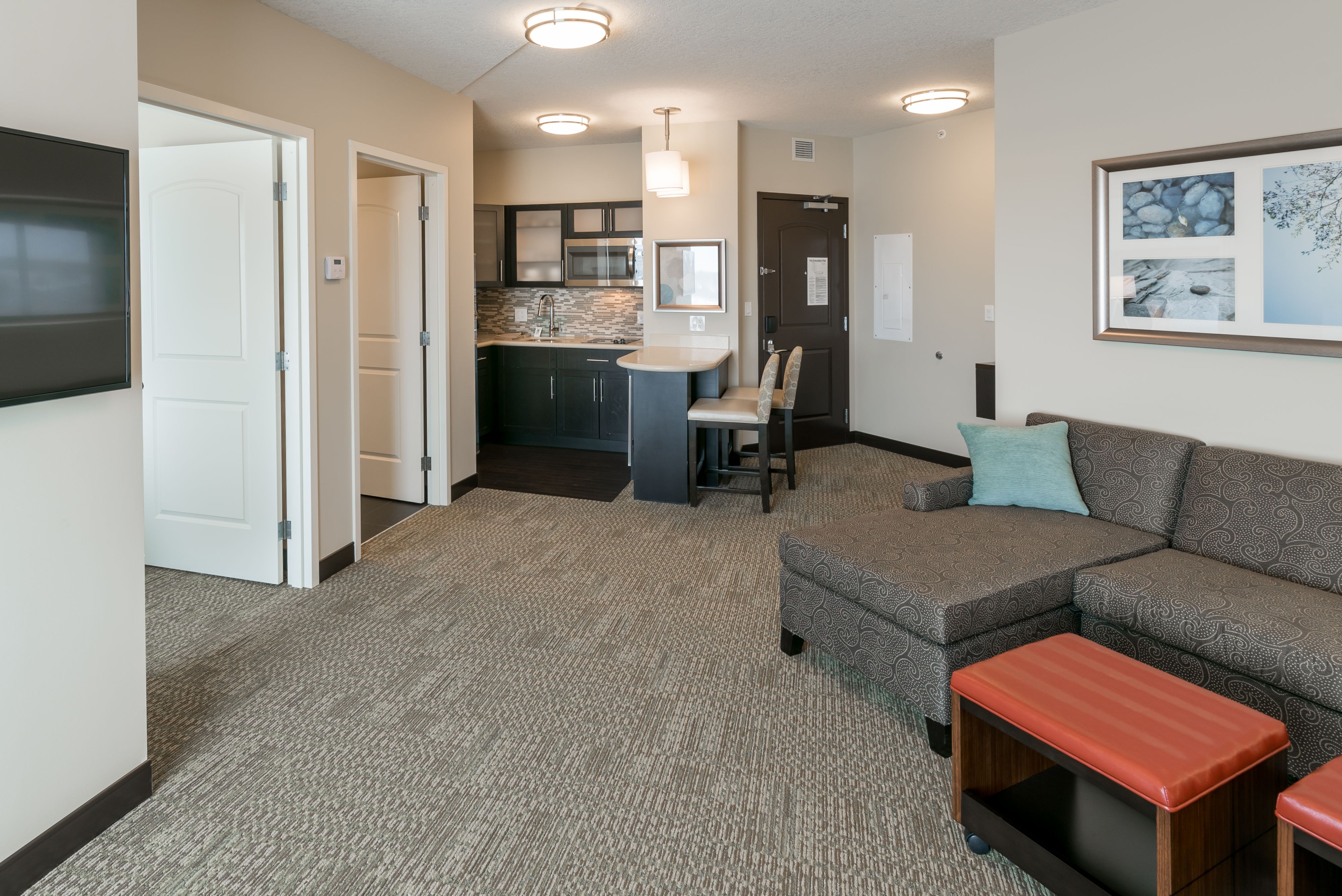 image Open living area with comfortable sofa and well-stocked kitchen nearby.