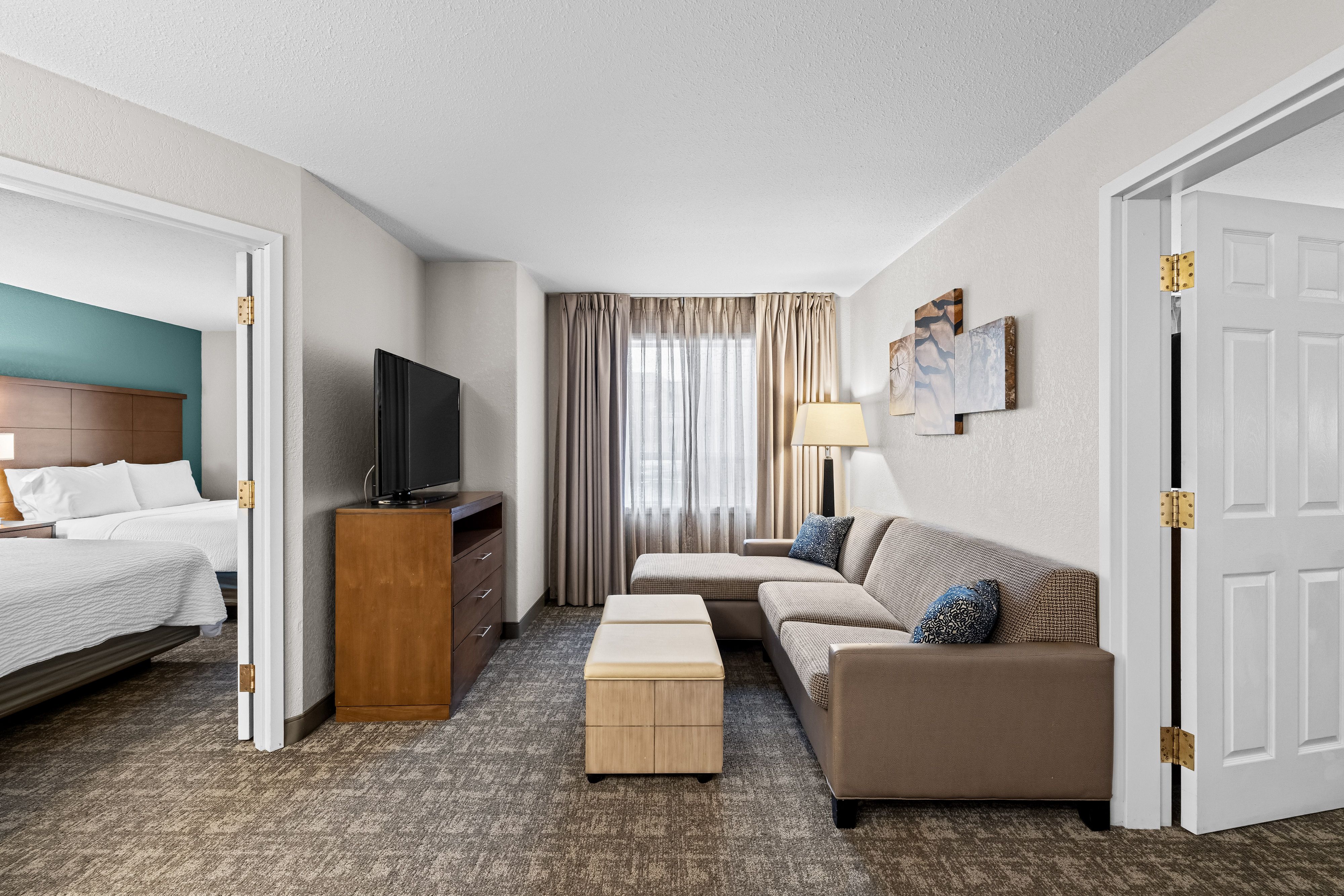 image Living area with sofa, flat-screen TV, and windows.