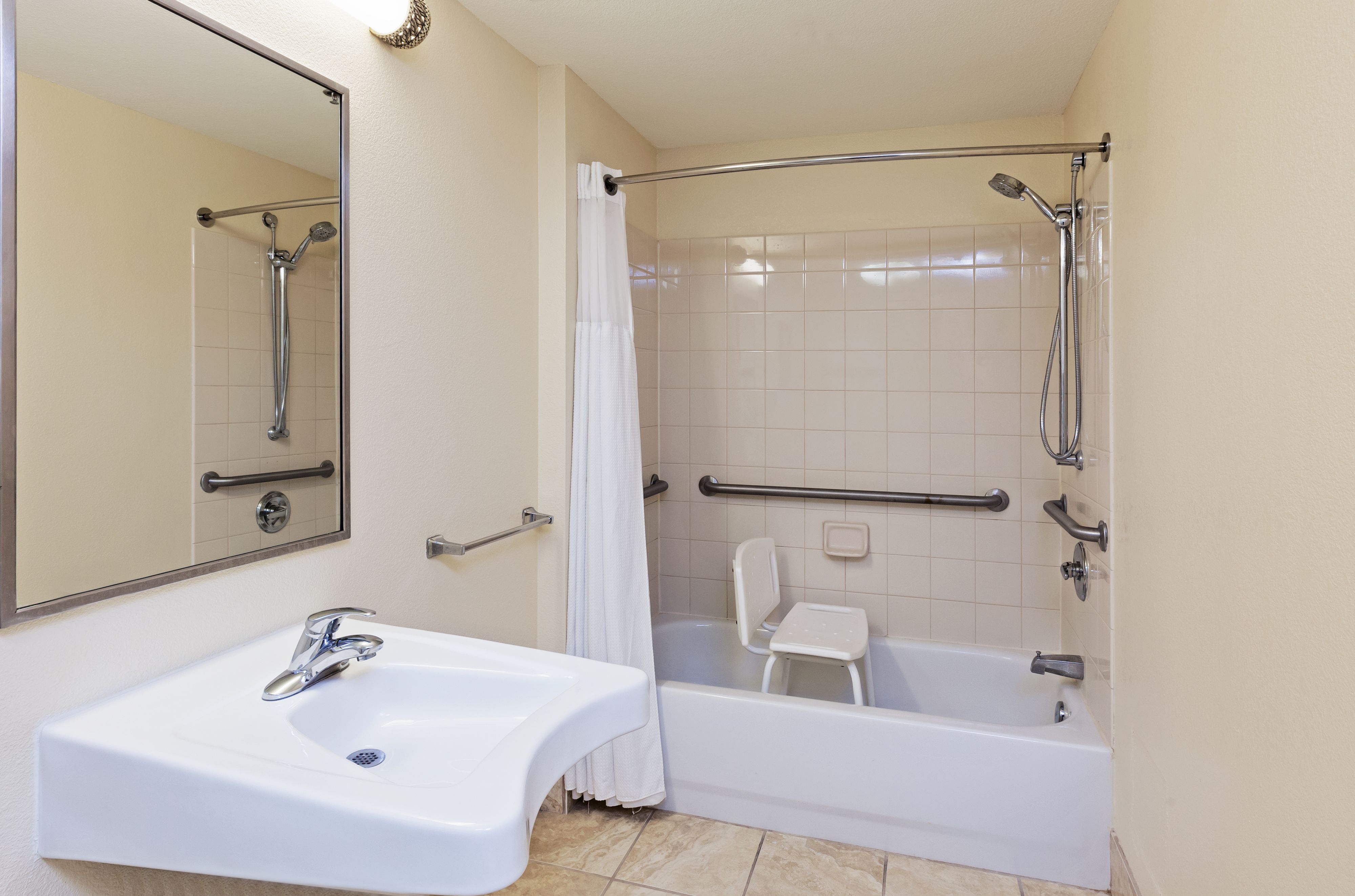 image Accessible bathroom with tub, grab bars, and sink.