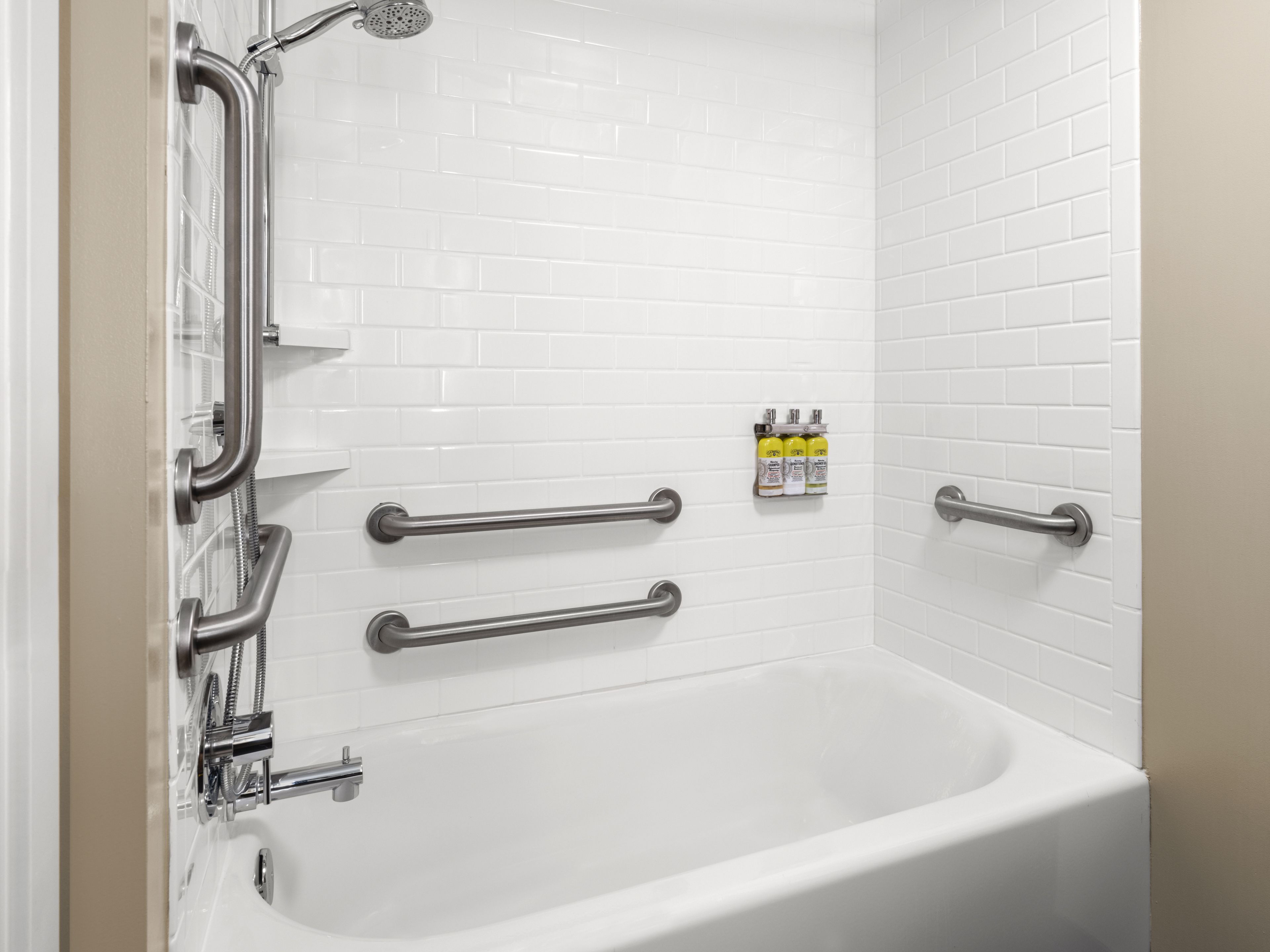image Accessible bathroom with tub, white tiles, and grab bars.