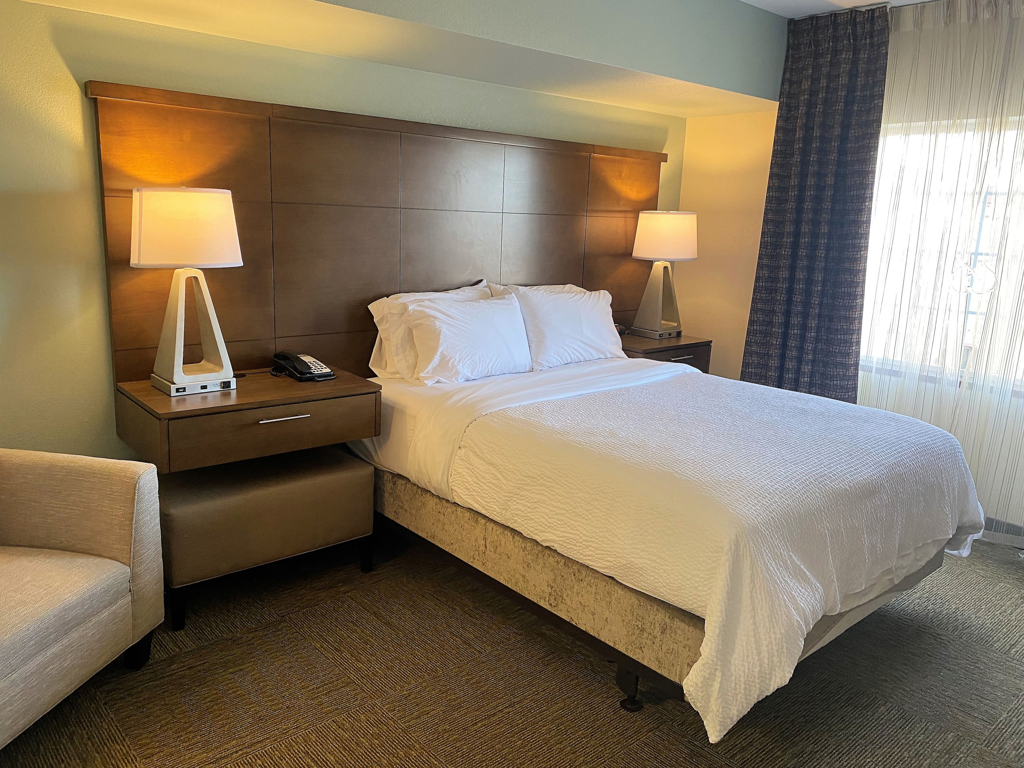 image Unwind in comfort with a stylish bedroom setup, complete with a cozy chair for your reading delight.