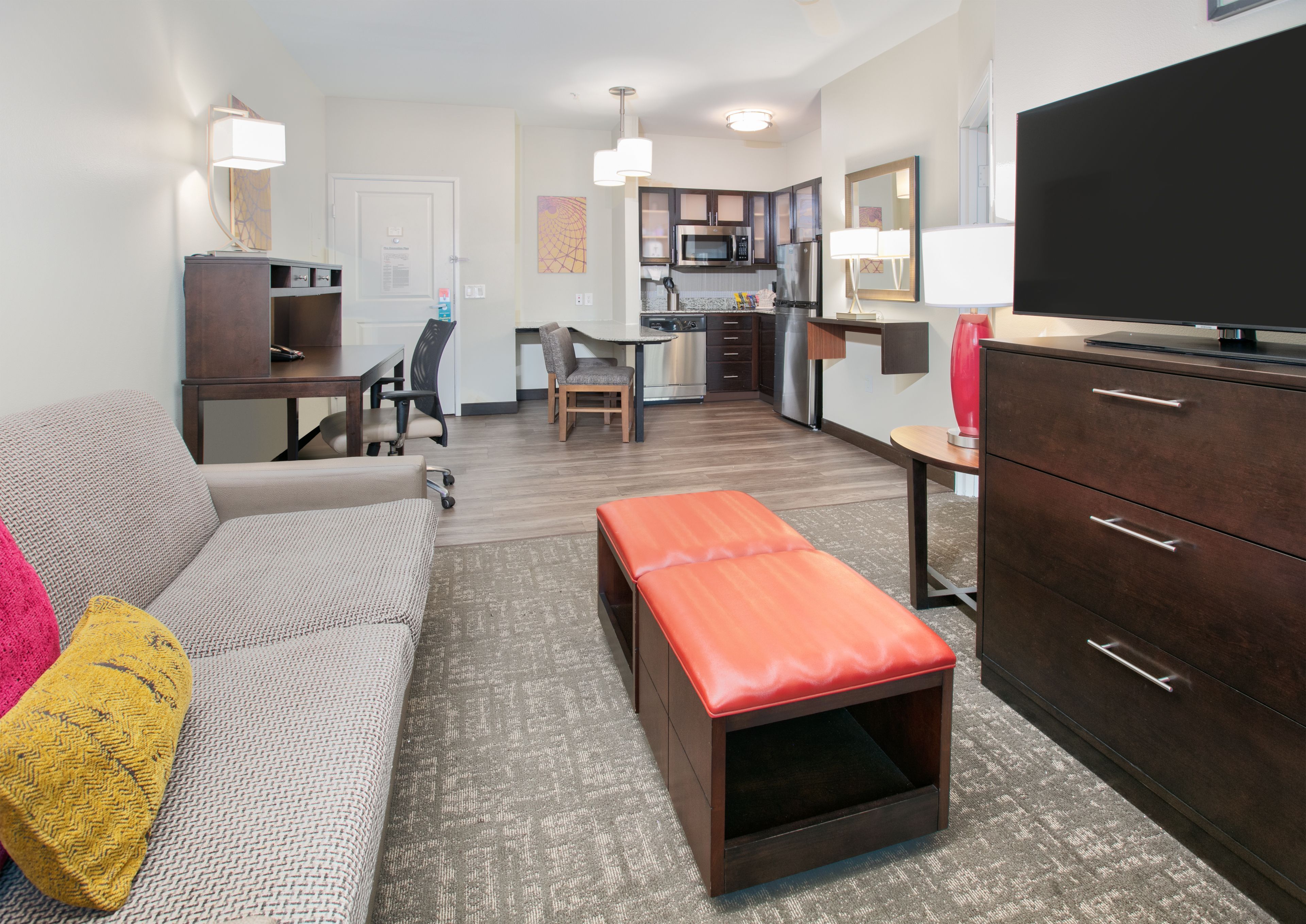 image Open suite living area with full kitchen, sofa seating, and flat-screen TV.