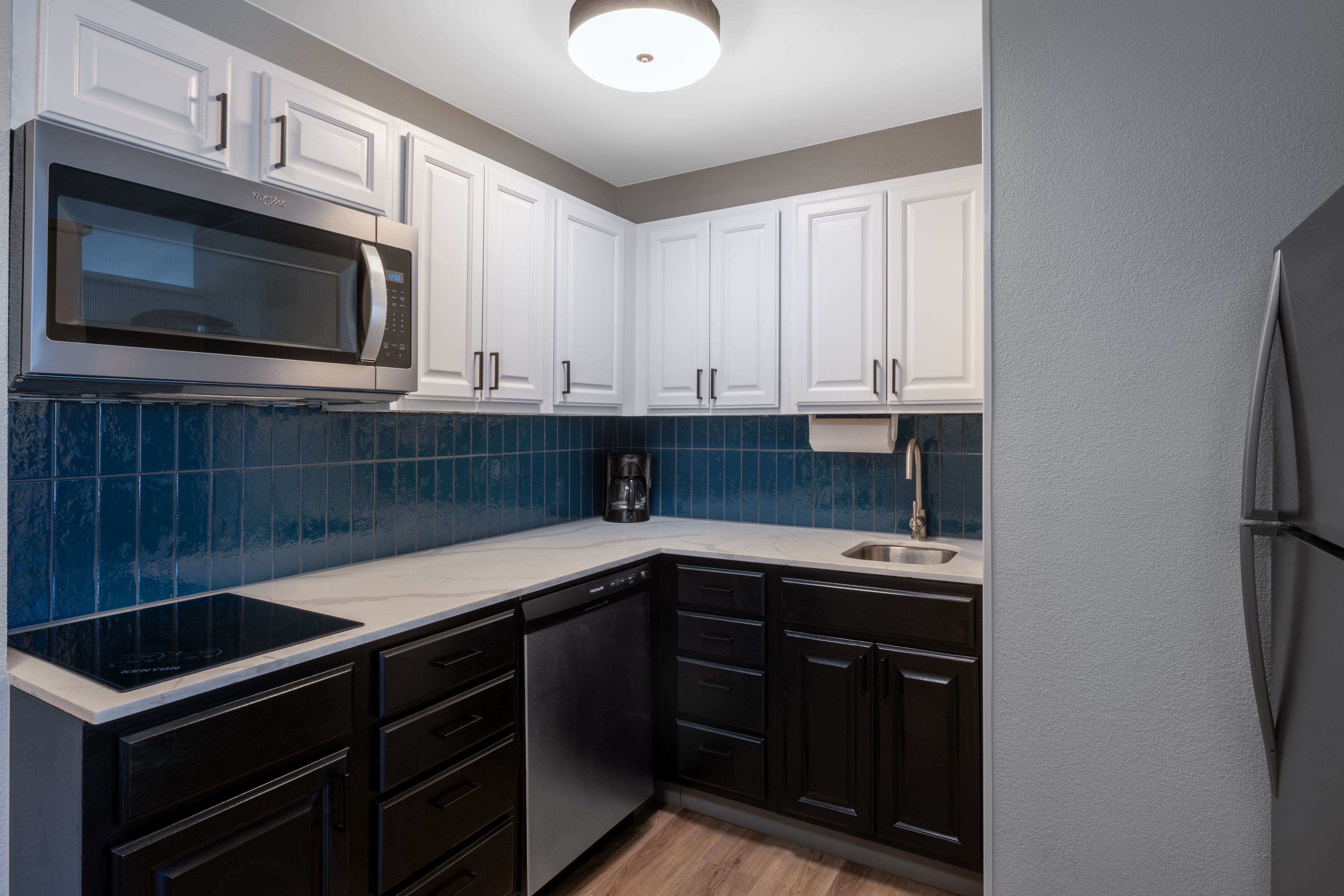 image Full kitchen with white and black cabinetry and modern appliances.