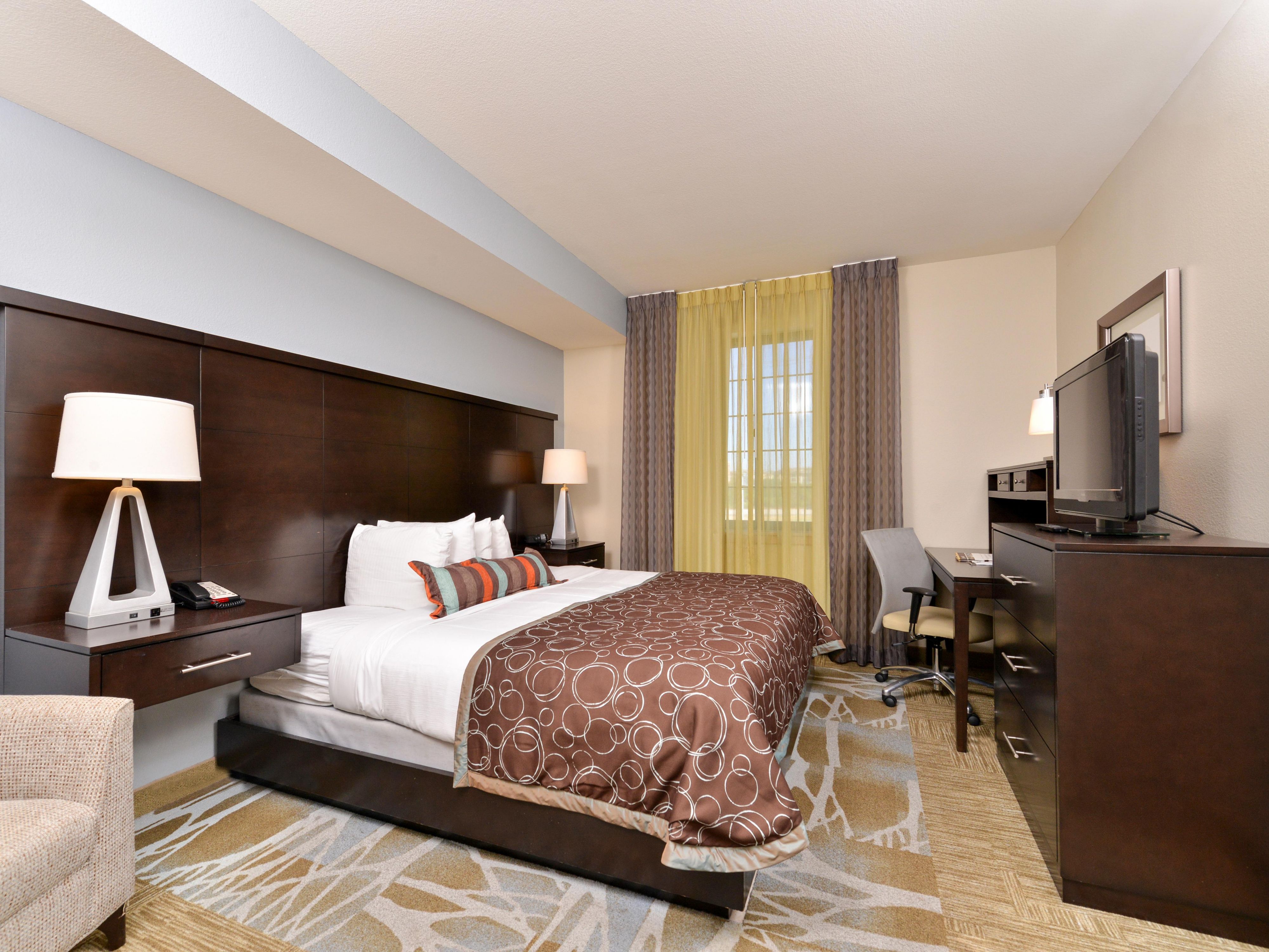 image Sleeping area with bed, desk, and flat-screen TV.