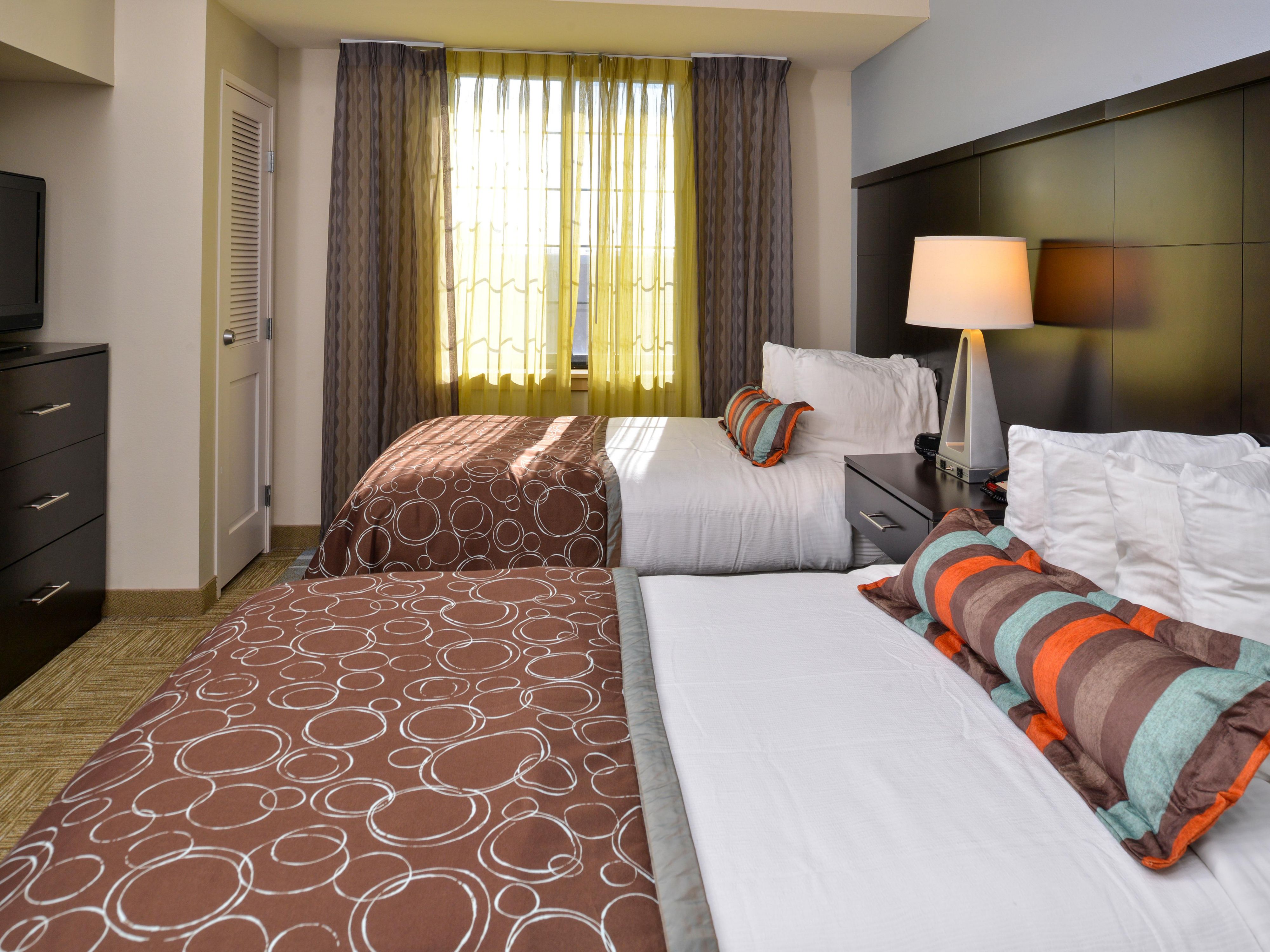 image Sleeping area with two queen beds, colorful pillows, and dresser.