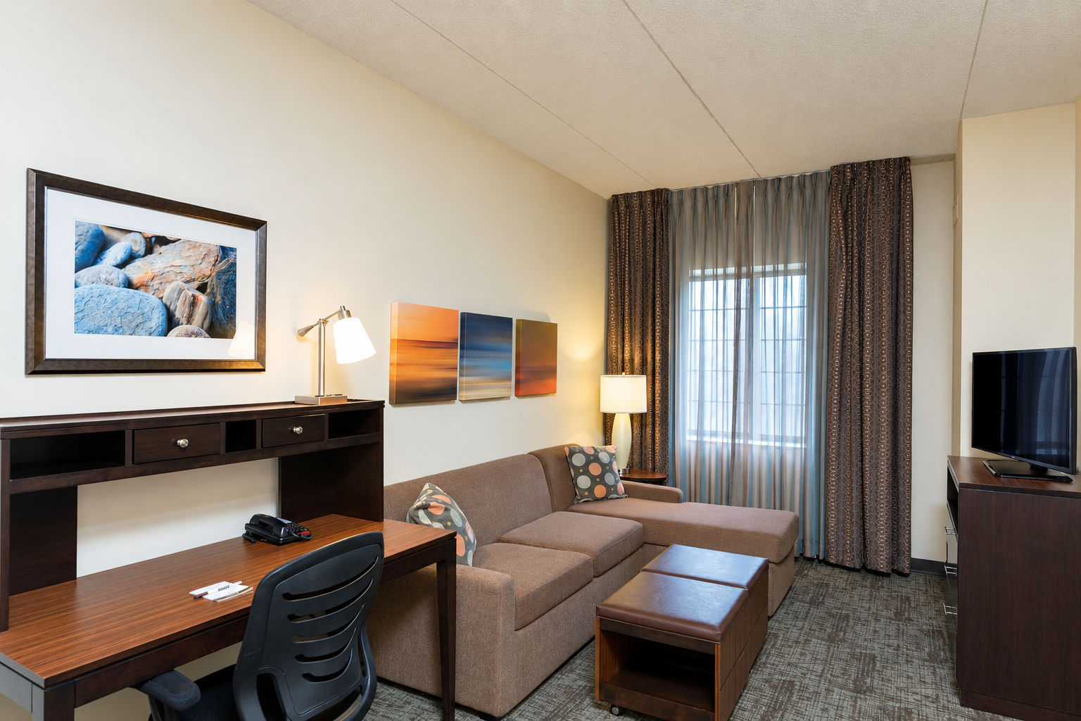 image Living area with sofa, desk, lamp, and wall artwork.
