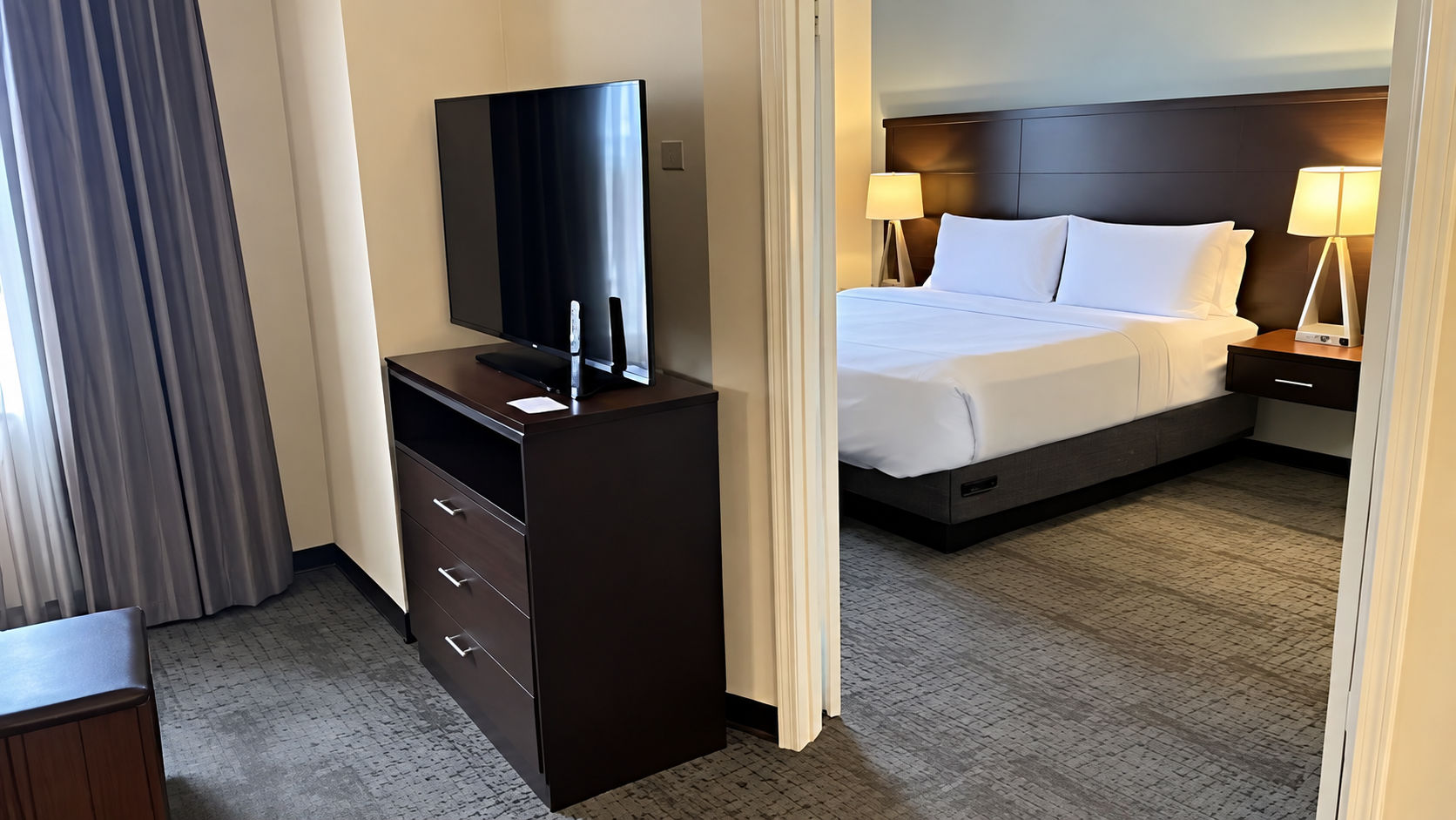 image Bedroom with queen bed, flat-screen TV, and bedside lamps.