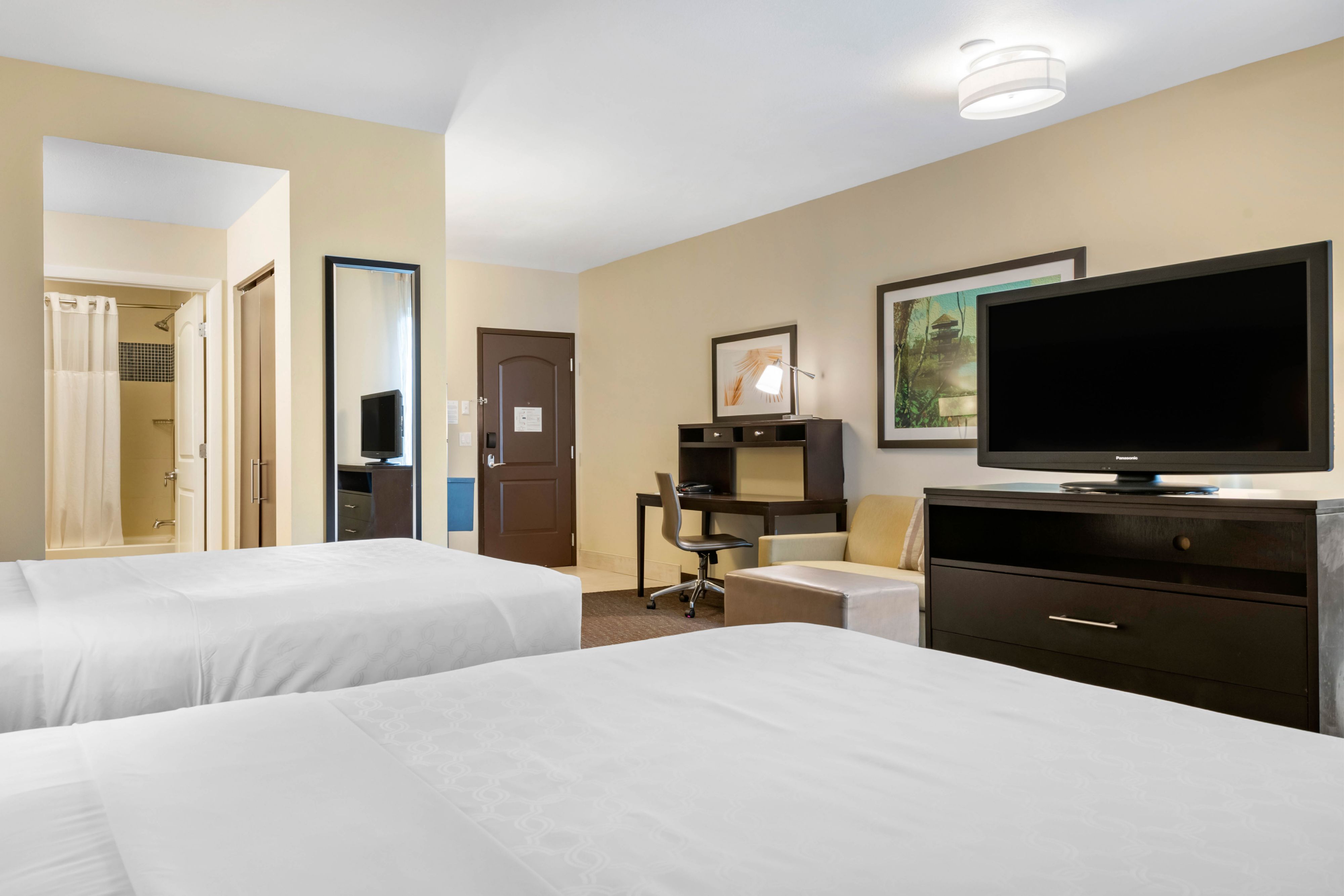 image Inviting room with two beds, a workspace, and flat-screen TV.