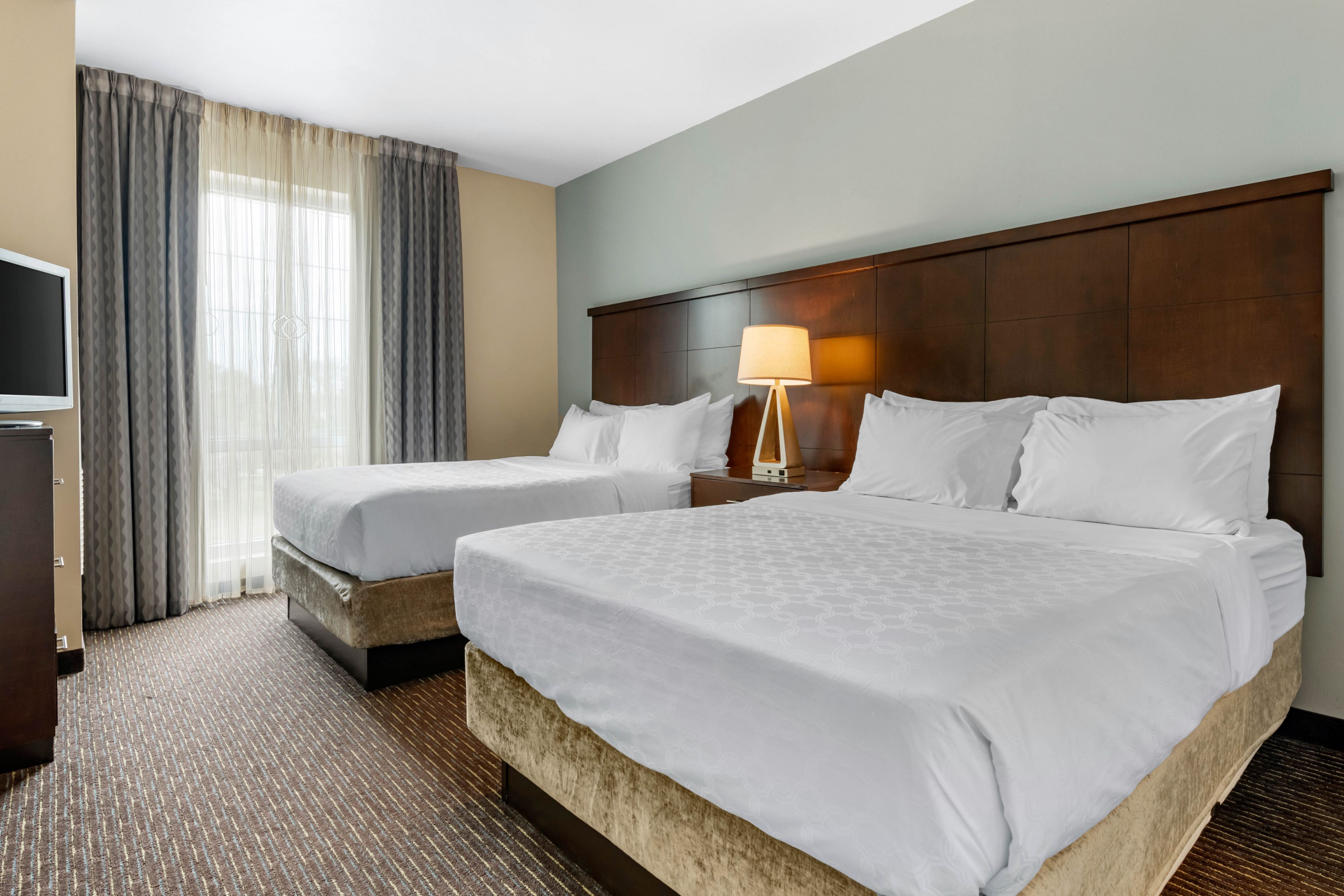 image Bright bedroom featuring two cozy queen beds and natural light.