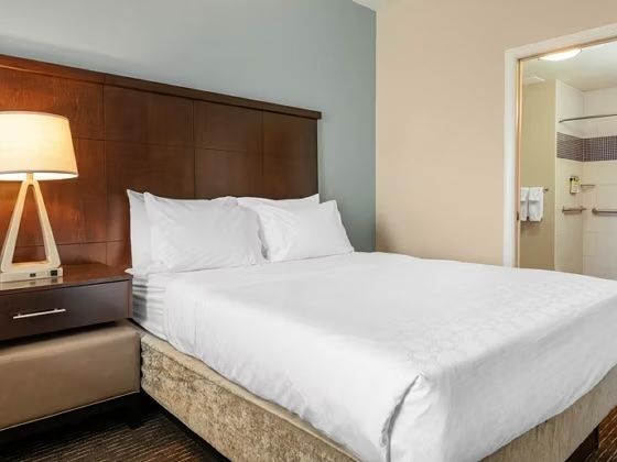 image Bedroom with king bed, light blue accent wall, and open doorway to bathroom