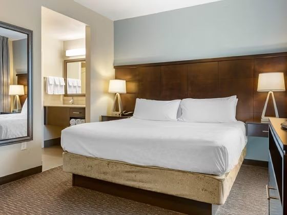 image King bed with dark headboard, dual bedside lamps, and bathroom entry with towel rack