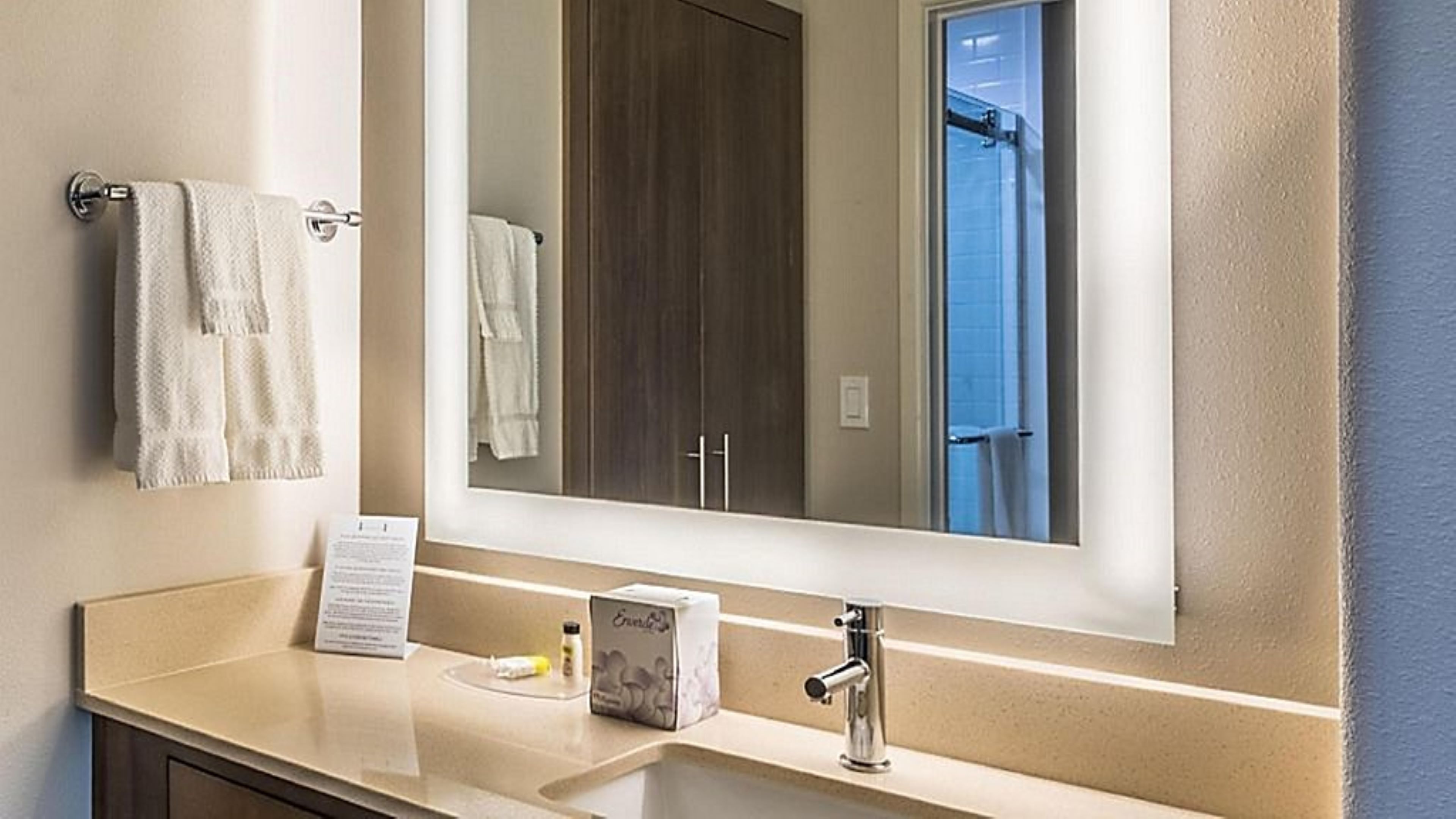 image Bathroom vanity with large illuminated mirror and storage.