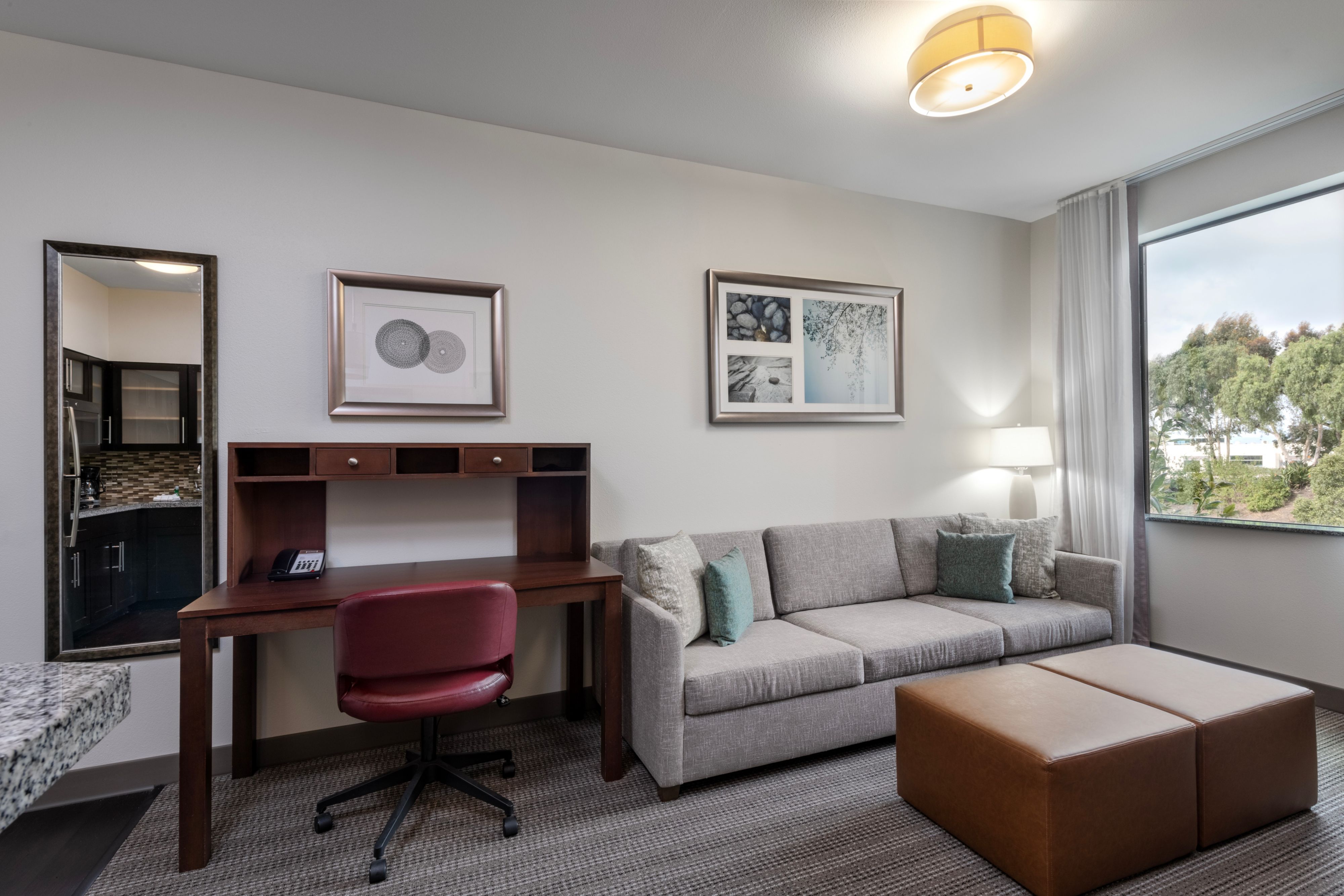 image Living area with a sofa, desk, and kitchenette in background.