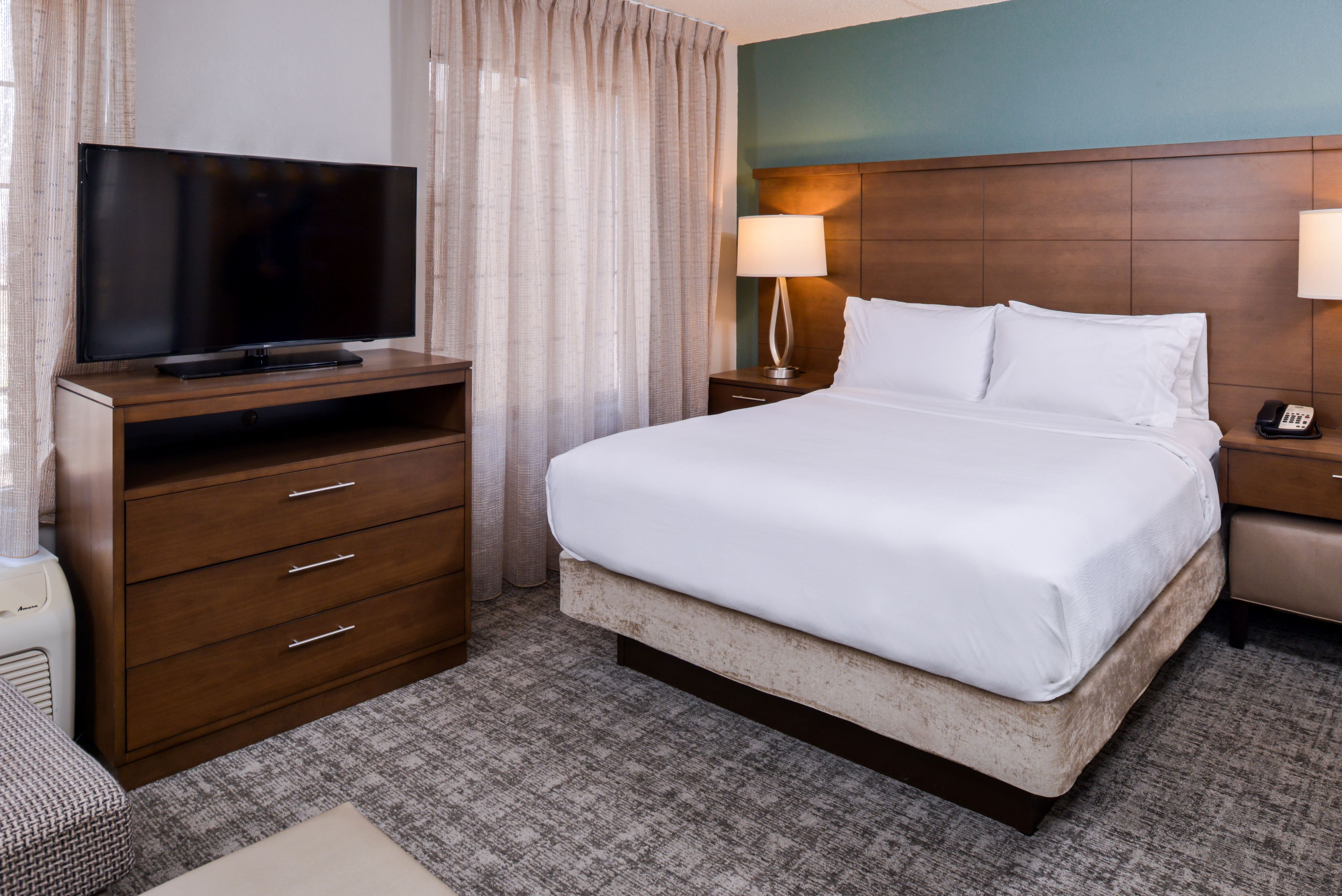 image Cozy king bedroom with flat-screen TV and neutral decor.