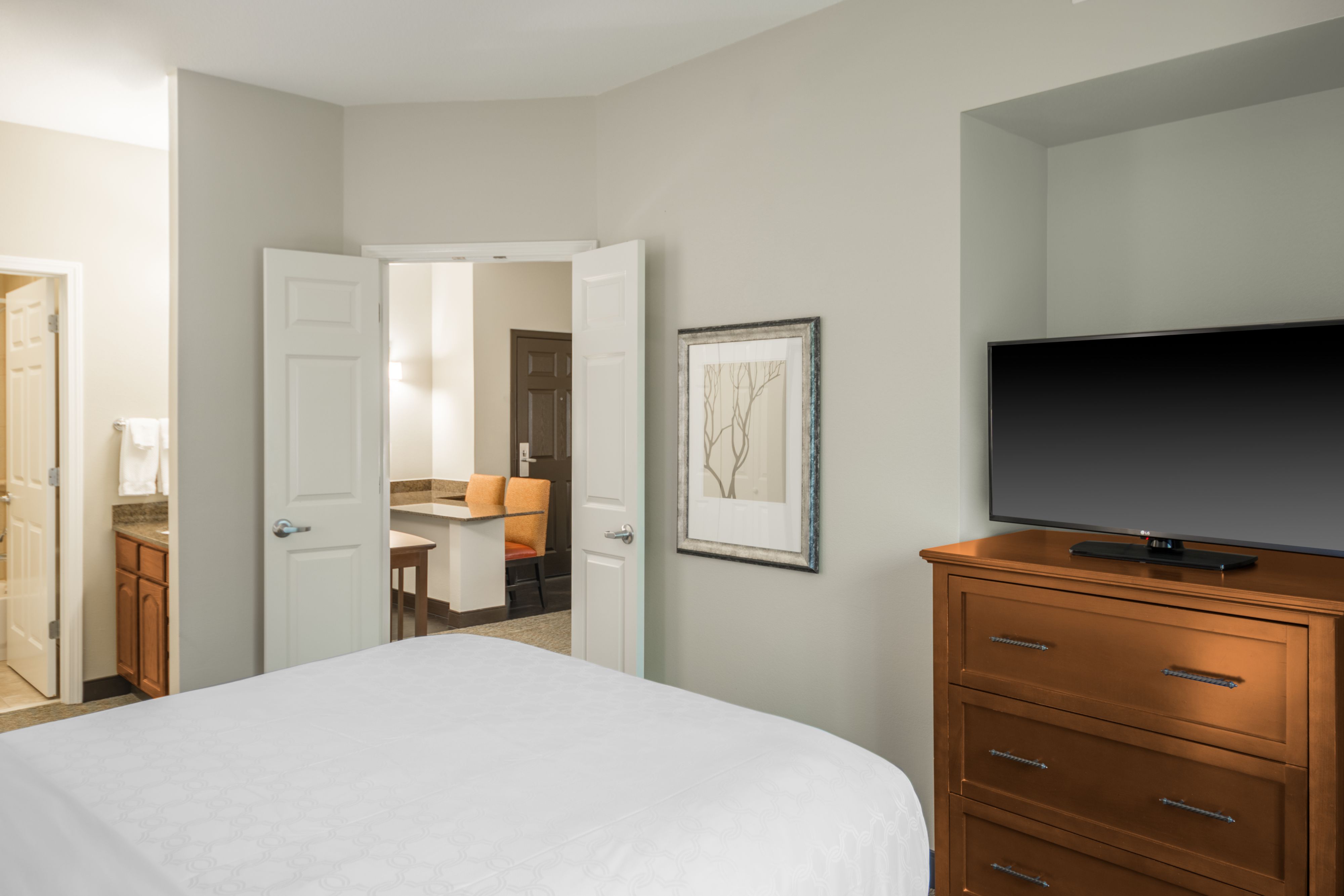 image Bedroom with TV, dresser, and open adjoining space.