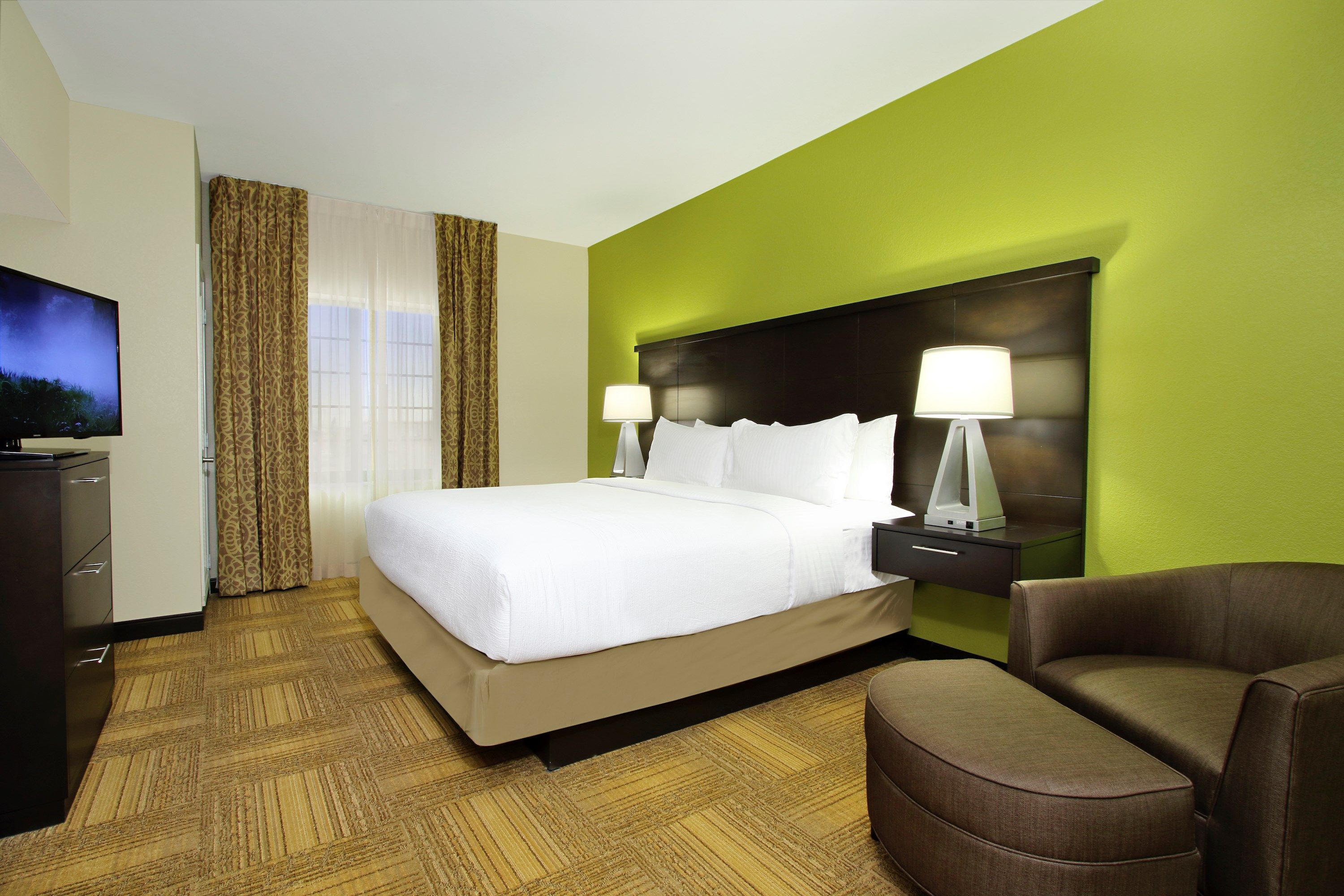 image Bedroom with king bed, accent wall, and bedside lamps.